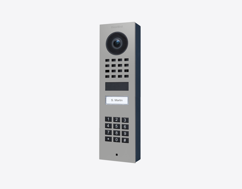 Surface-mount video door station with camera lens, keypad and call button, light gray metal