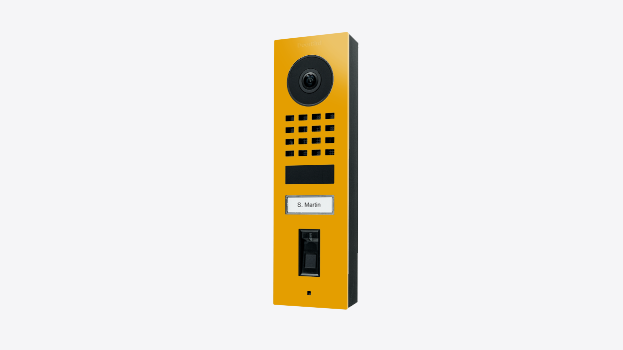 DoorBird video door station in golden yellow, front with camera and keypad