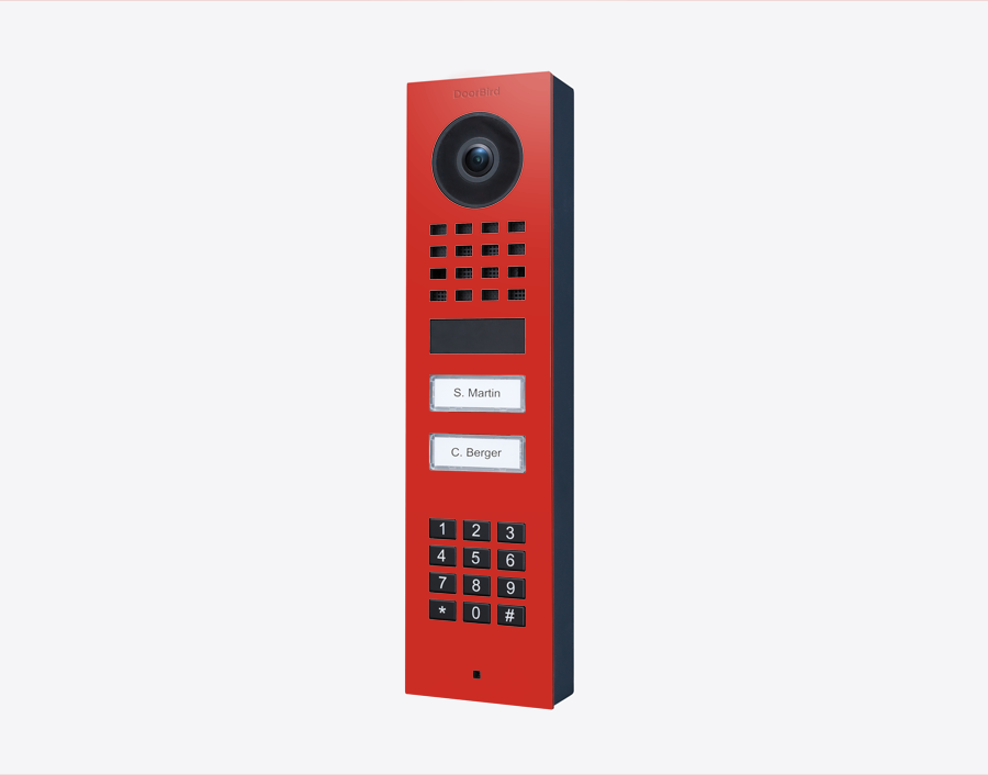 DoorBird surface-mount video door station in pure red with camera, keypad, and two call buttons