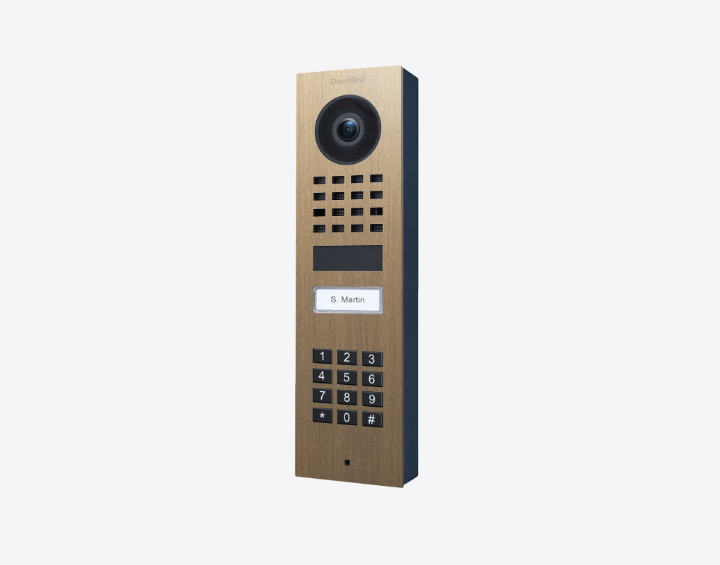 Surface-mount video door station with burnished brass face, camera lens, keypad