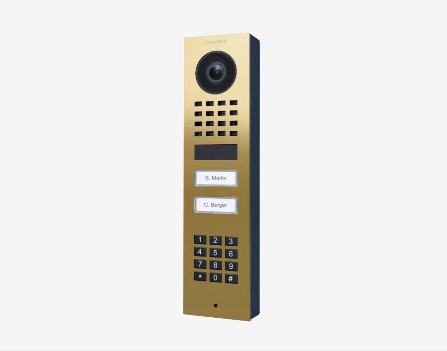 DoorBird brass surface-mount IP video door station with camera lens, keypad, and two call buttons