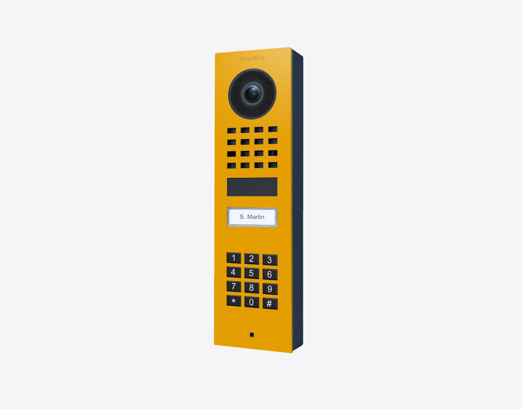 DoorBird D1101KV surface-mount video door station in golden yellow with camera and keypad
