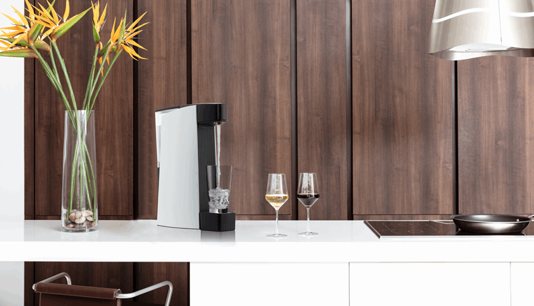 Carbon8 sparkling water maker on countertop with two glasses
