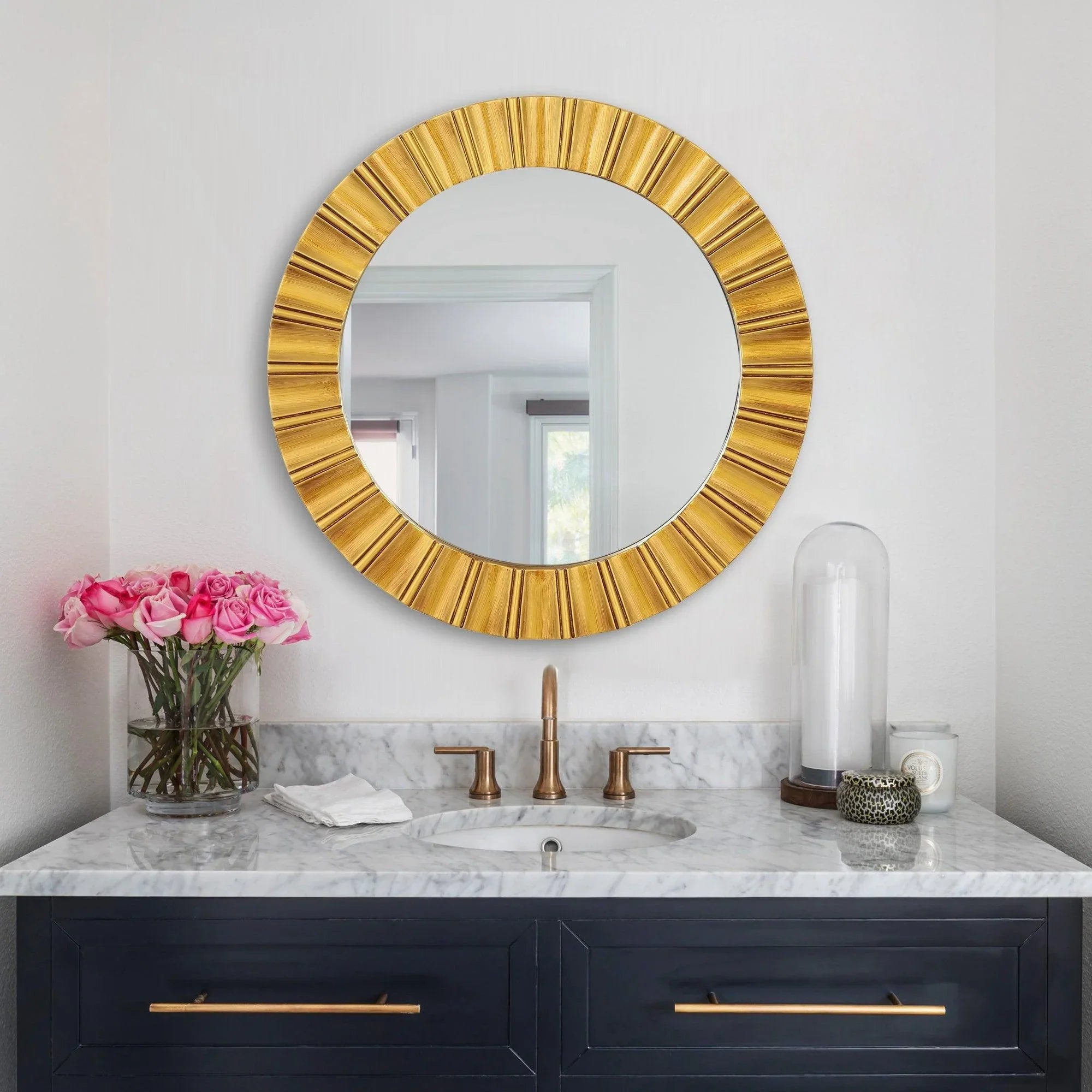 Golden round wall mirror with ribbed sunburst-style frame and clear reflective center