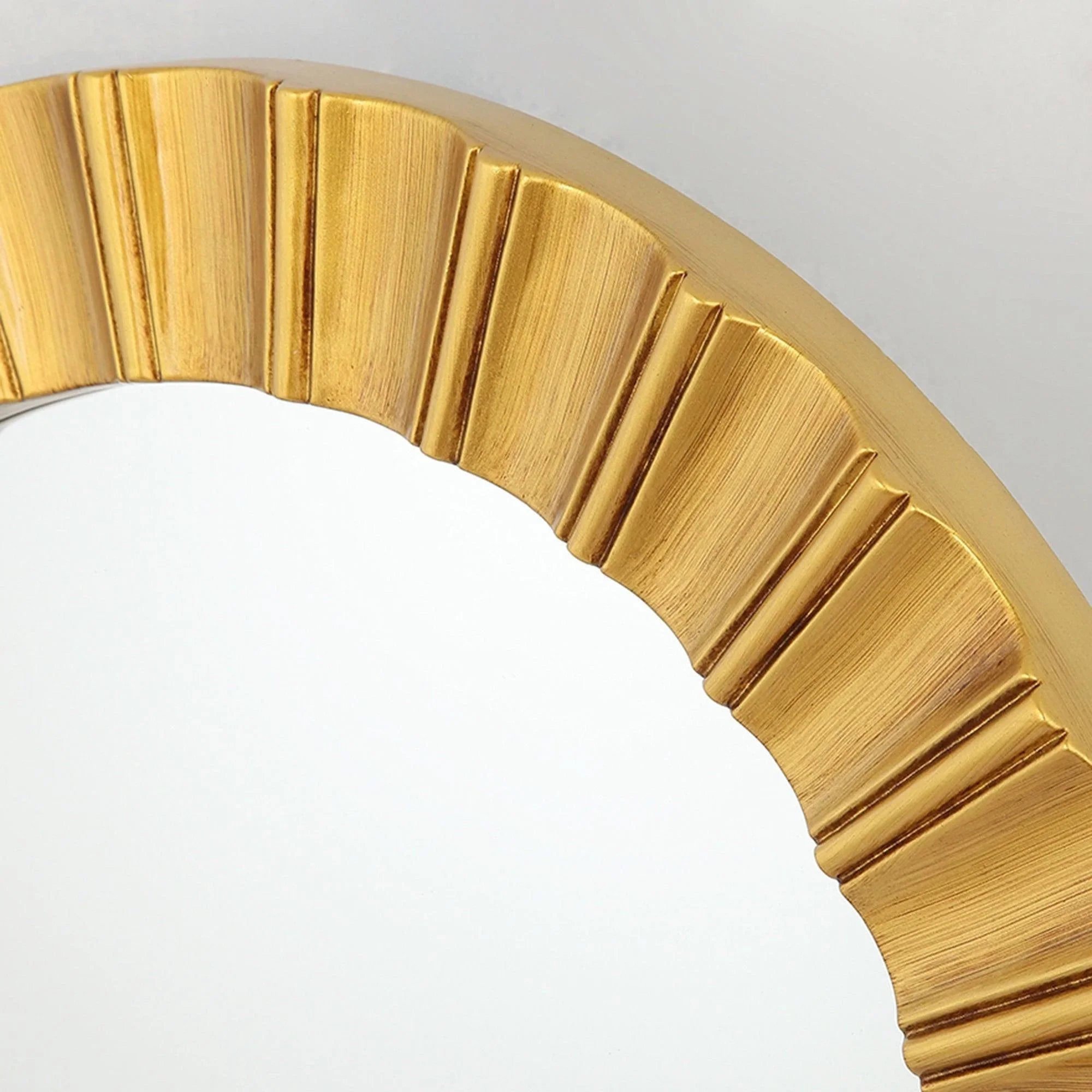 Close-up of golden ribbed sunburst frame detail on a round wall mirror
