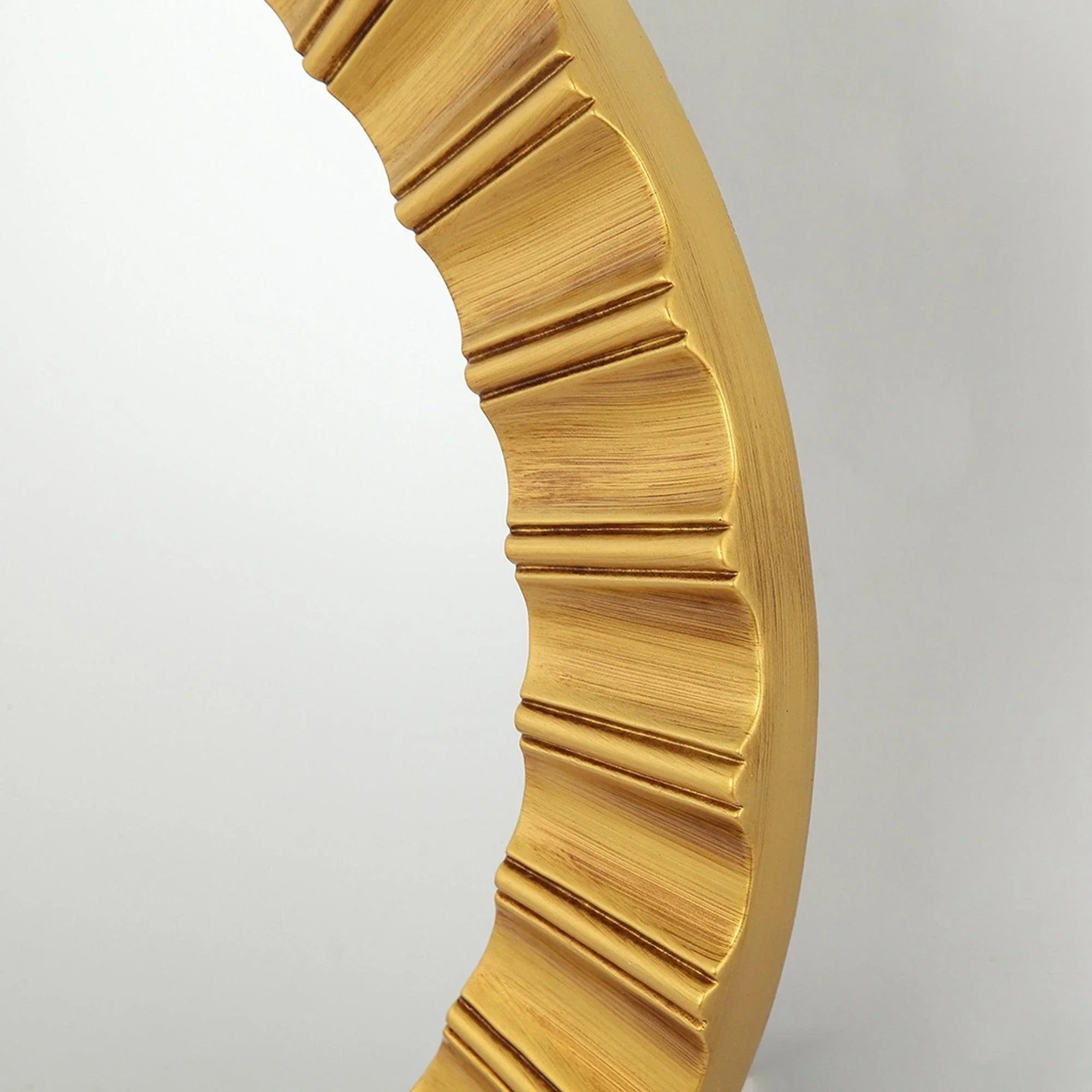 Close-up of the golden ribbed edge on a round wall mirror frame