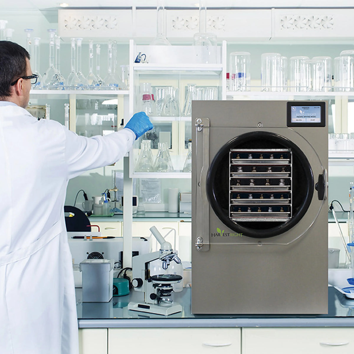 Lab technician operating a stainless steel freeze dryer in a laboratory setting