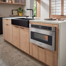 Stainless microwave drawer built into cabinetry with black control panel and window