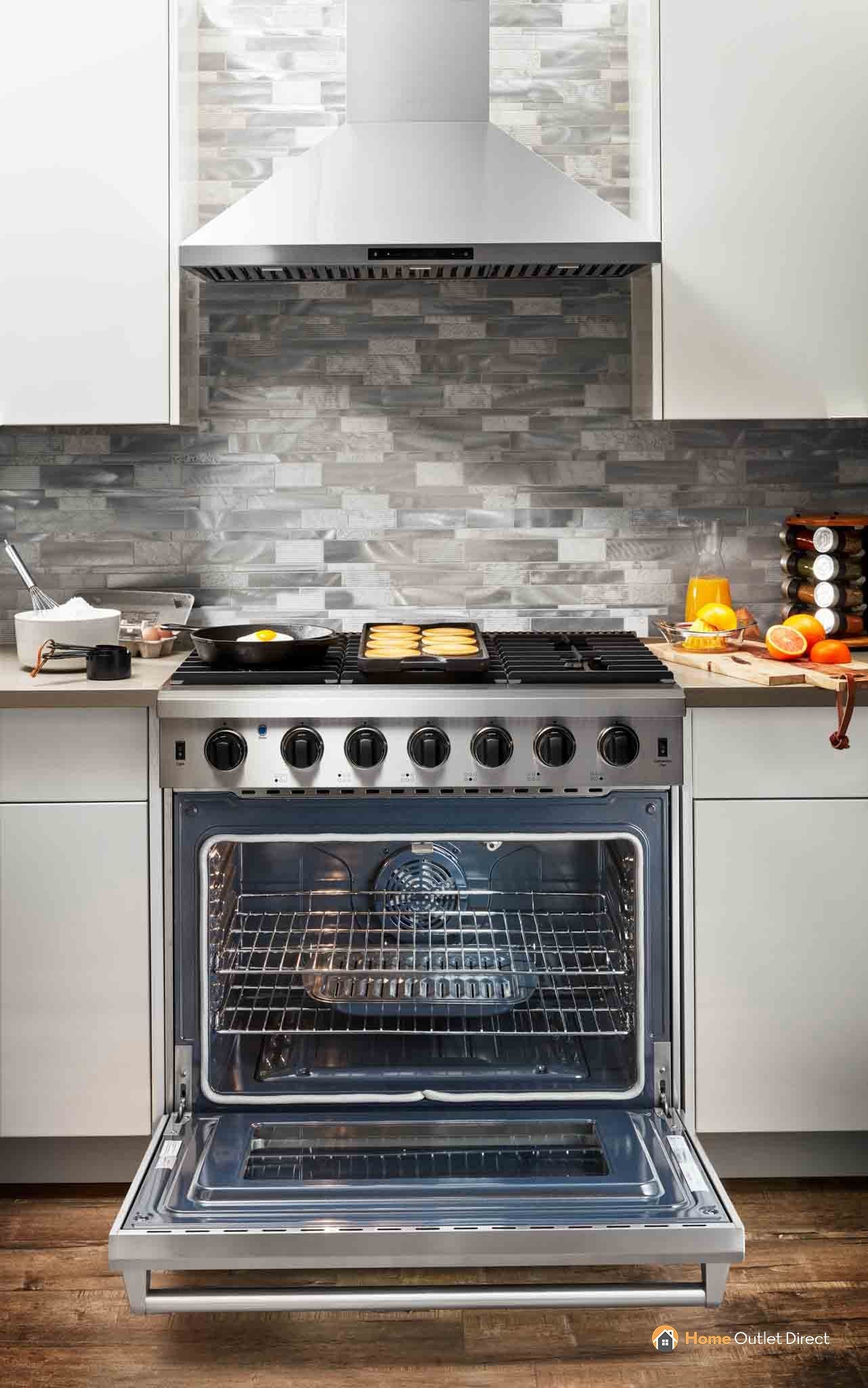 Stainless steel gas range with open oven and storage drawer below the door