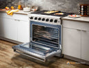 Stainless steel gas range with open oven and flat metal broiler tray on floor