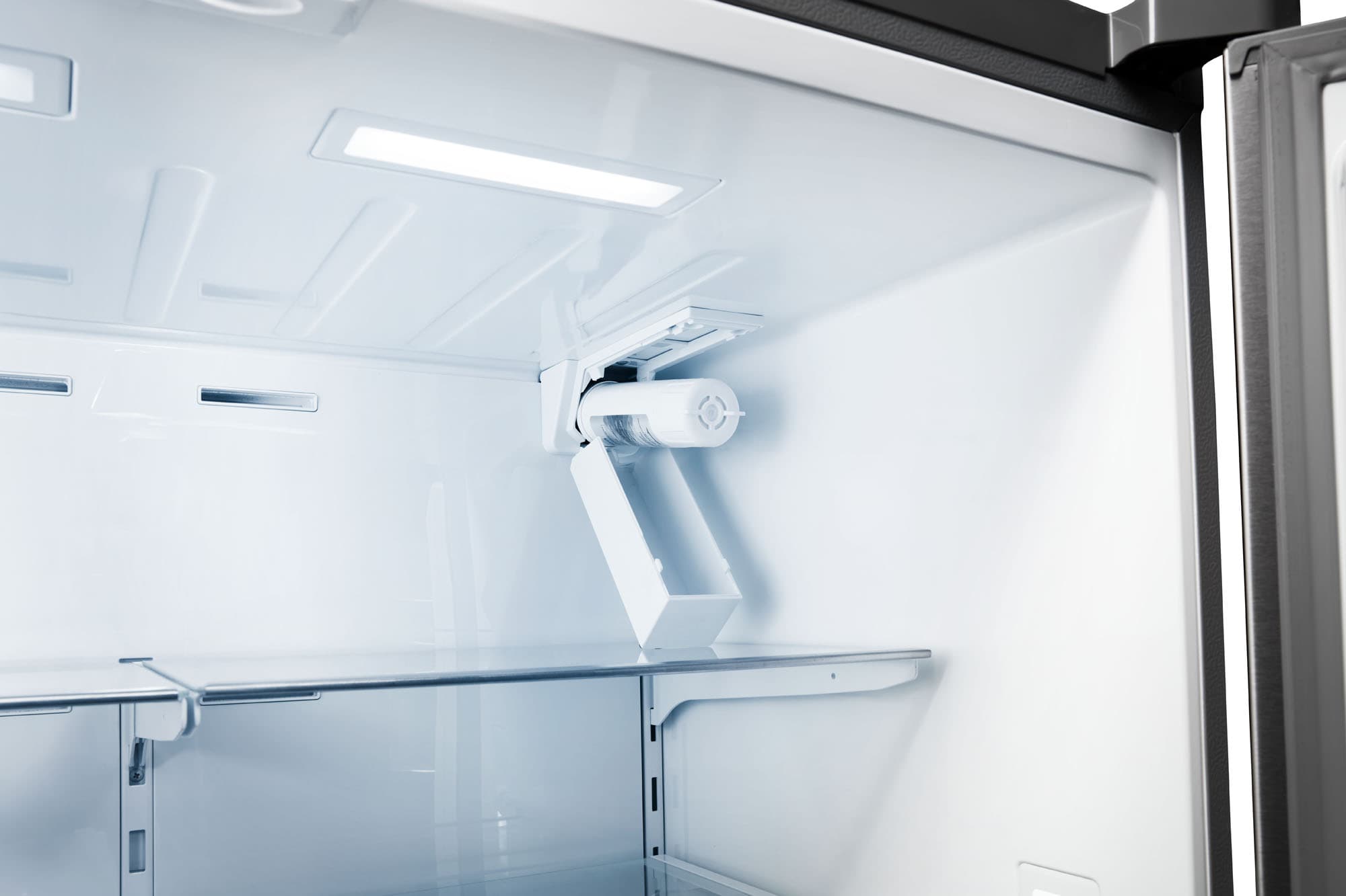 Refrigerator interior with overhead light, fan vent, and adjustable upper shelf