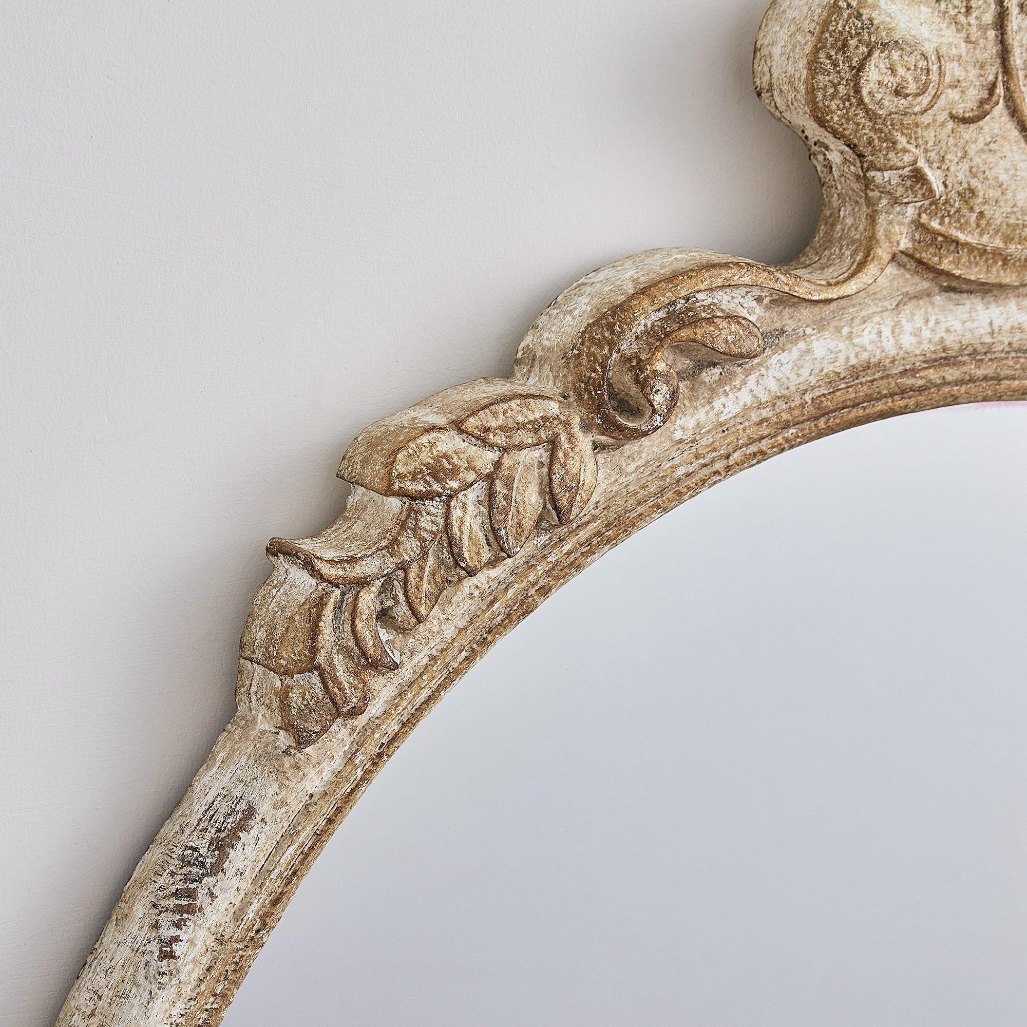Close-up of ornate distressed wood mirror frame with carved floral accents.