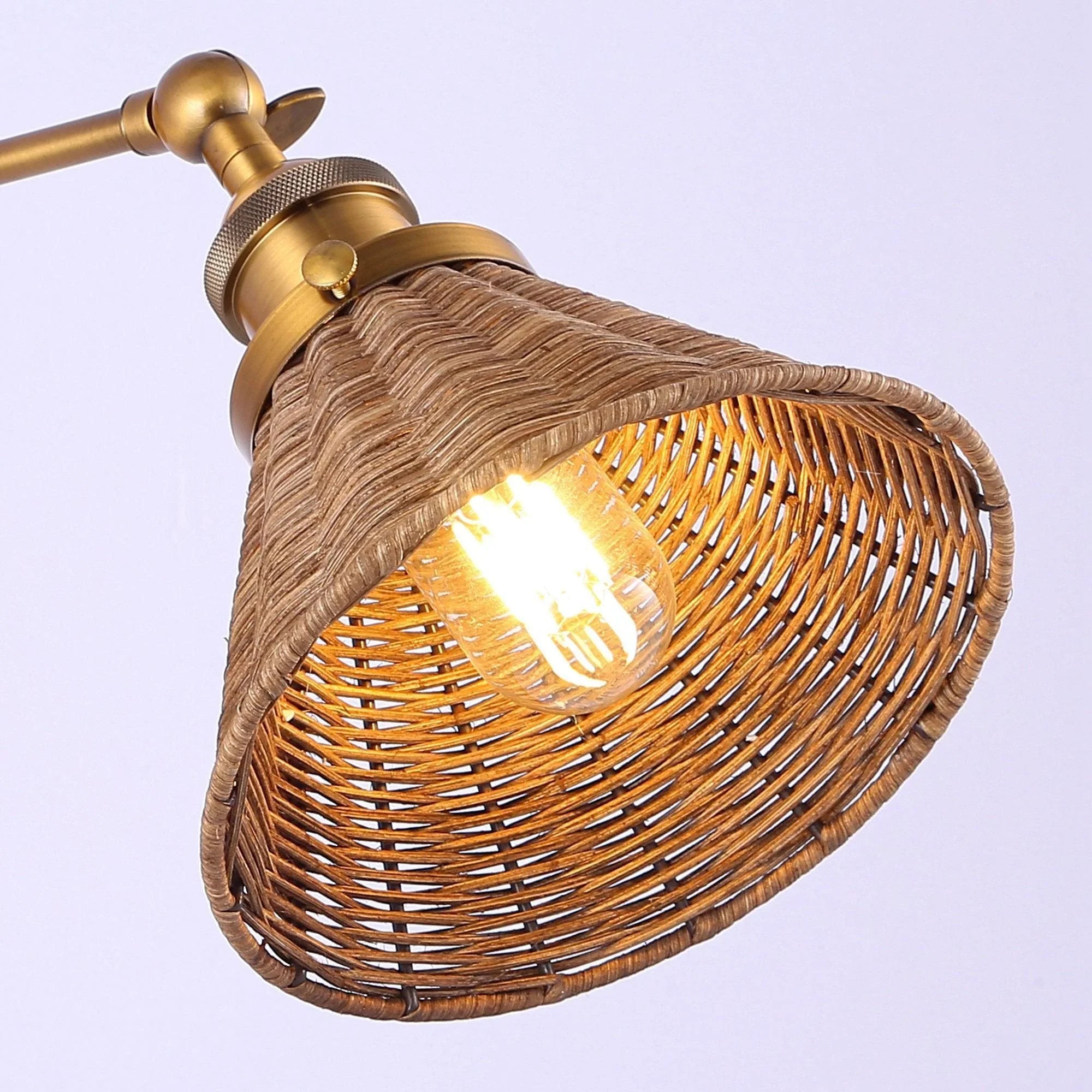Golden wall sconce close-up with rattan shade, glowing bulb visible through lattice weave