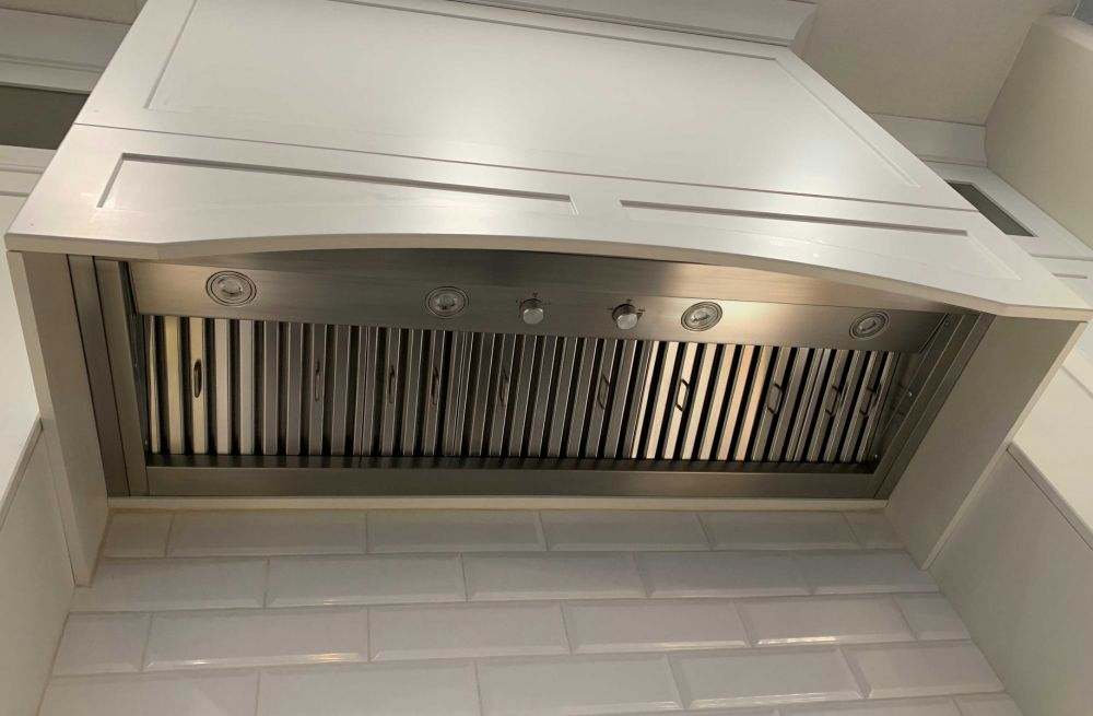 Stainless steel range hood insert installed under cabinet, front controls and grille