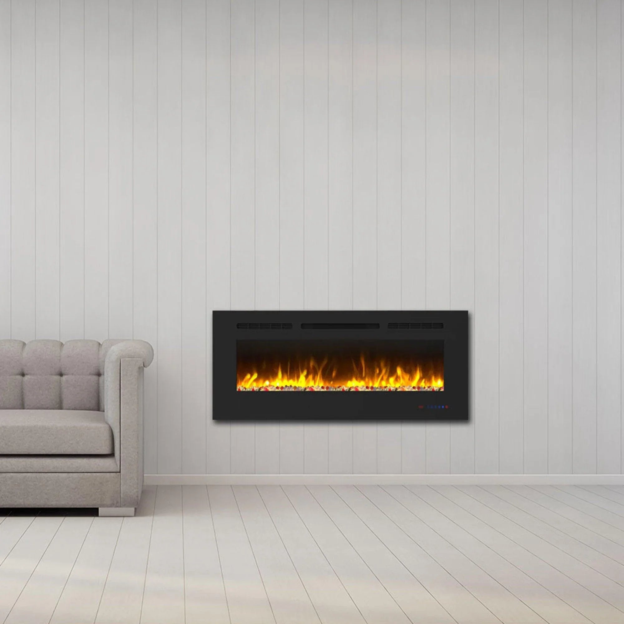 Black electric fireplace with orange flame effect mounted on a white wall near a gray sofa