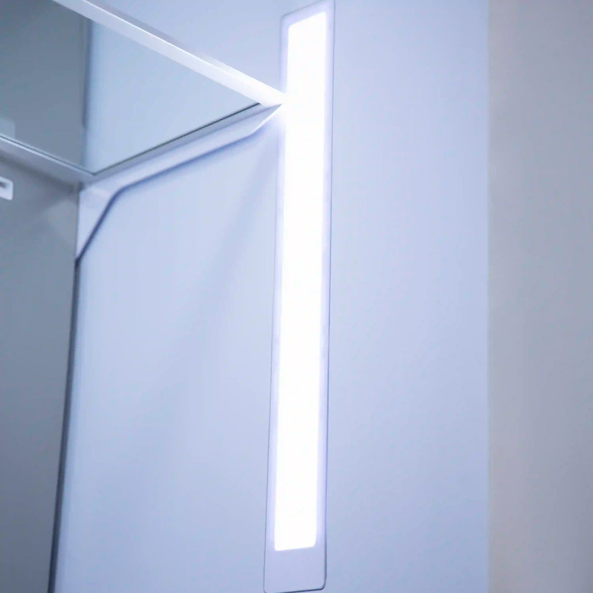 Refrigerator interior with bright vertical light strip along the door