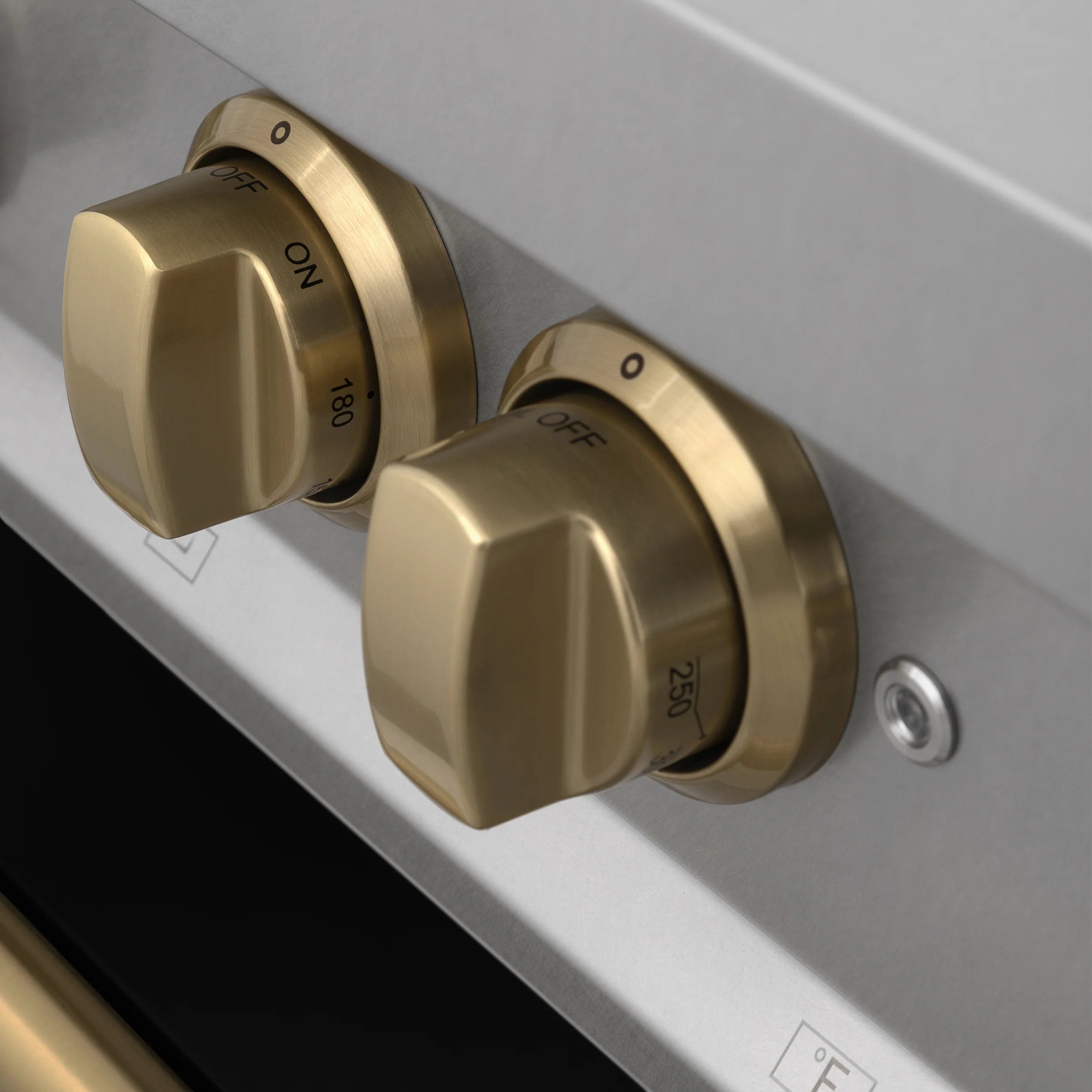 Dual fuel range pair of champagne bronze control knobs on black/gray panel