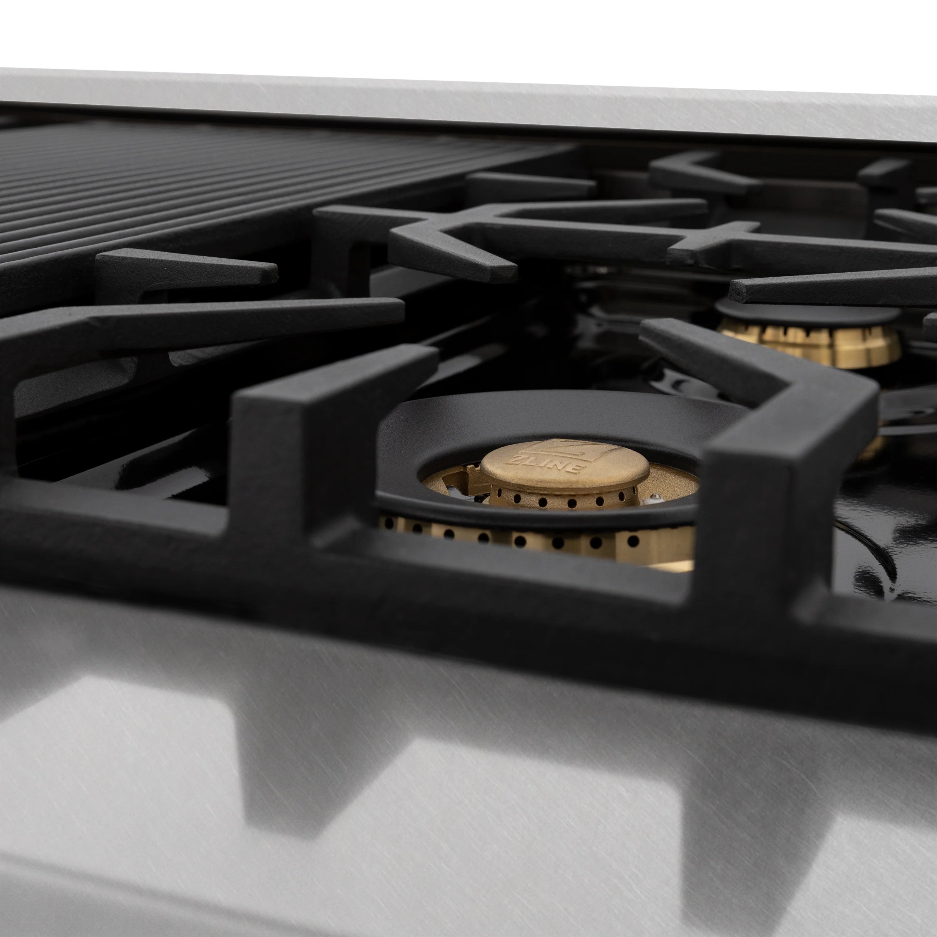 Gas burner grate with brass burner head on a black cooktop surface