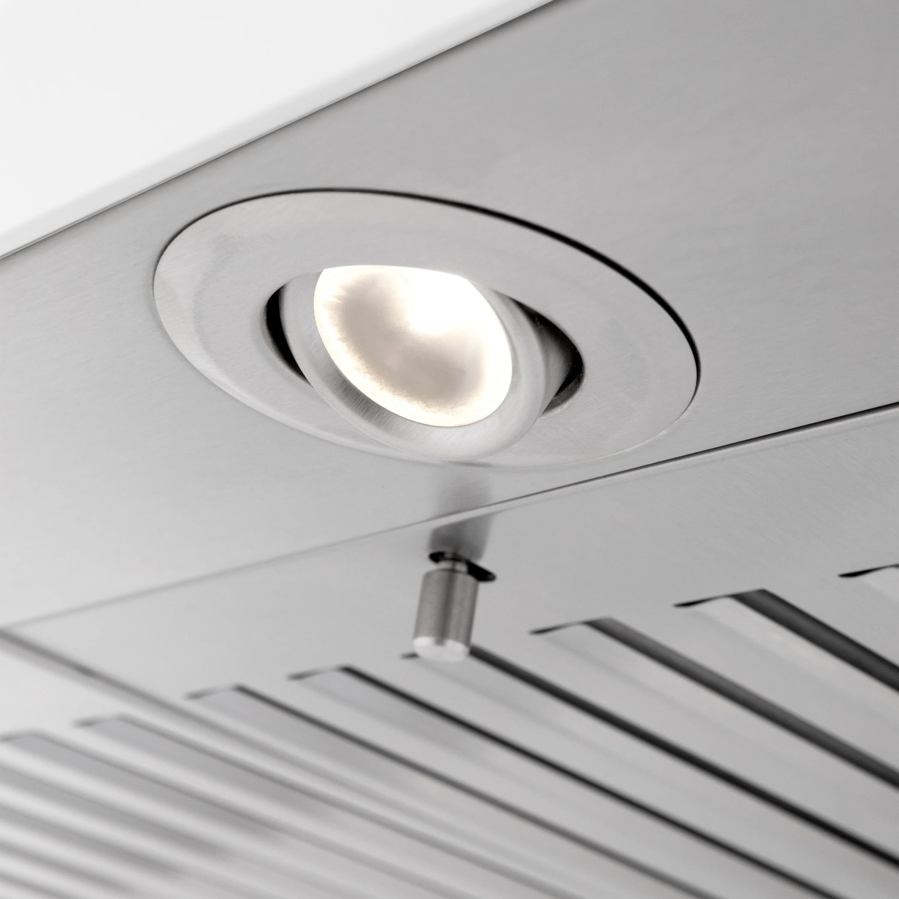 Round recessed light inside a white range hood over vent filters