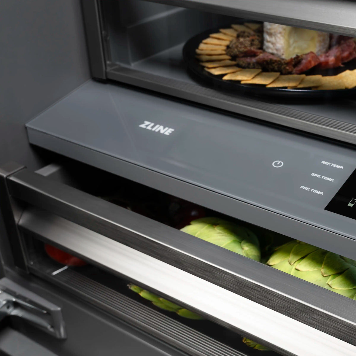 Built-in refrigerator lower drawer with control panel and clear bins holding green produce.