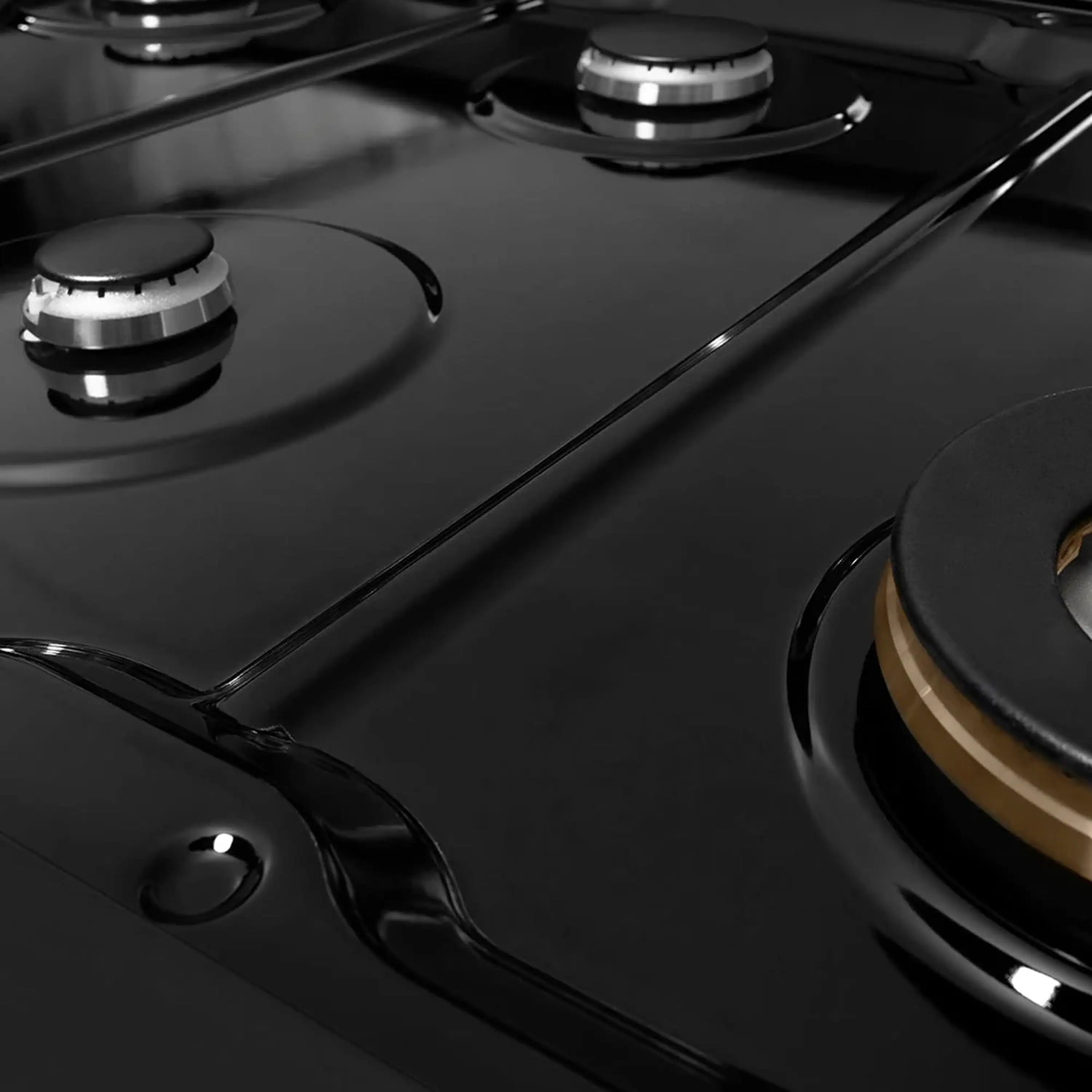 Close-up of black gas cooktop with burner caps and glossy porcelain surface