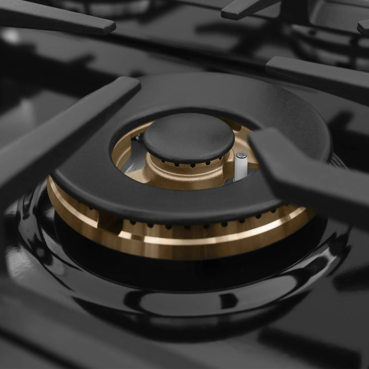 Single gas burner on black cooktop with champagne bronze burner base and grate cap