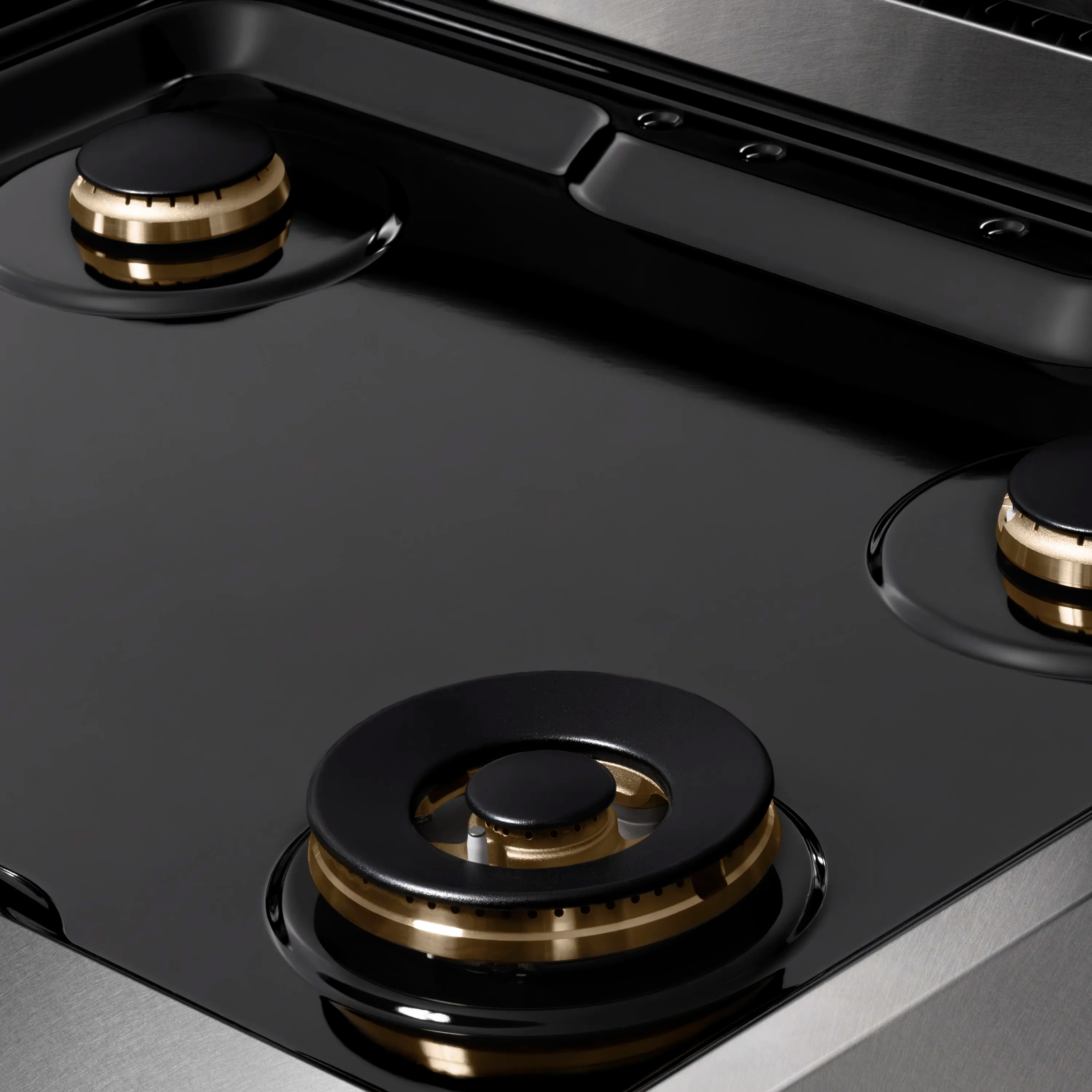 Gas burner on satin stainless steel cooktop with black burner head and bronze ring