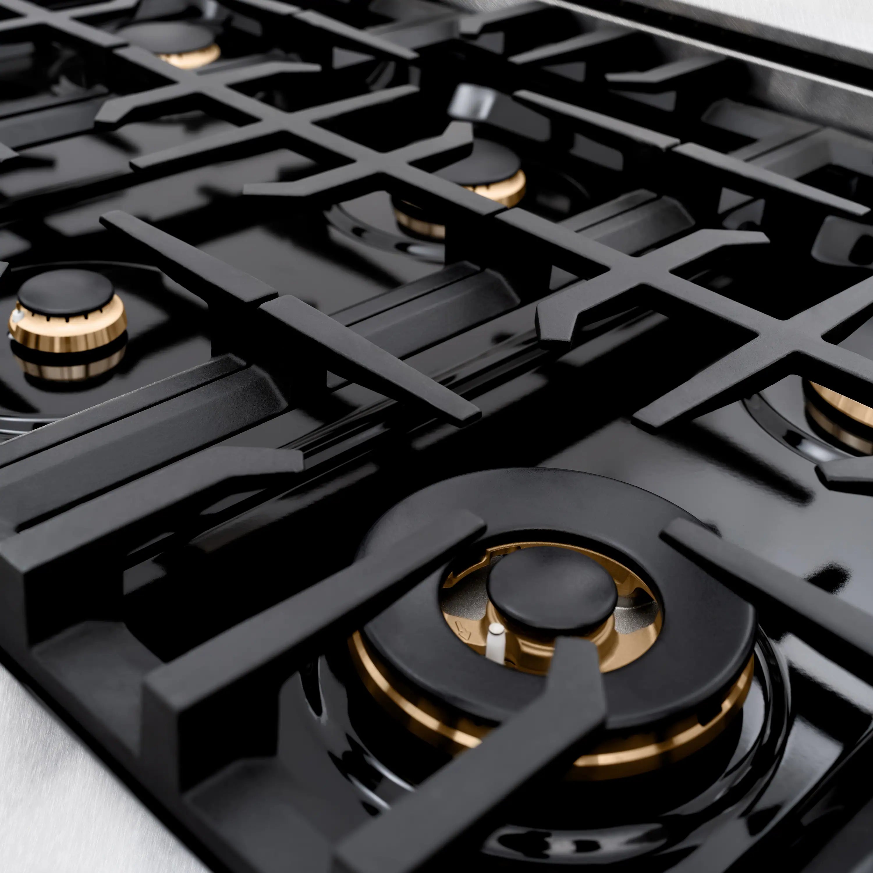 Black gas cooktop with cast grates and round gold burner controls