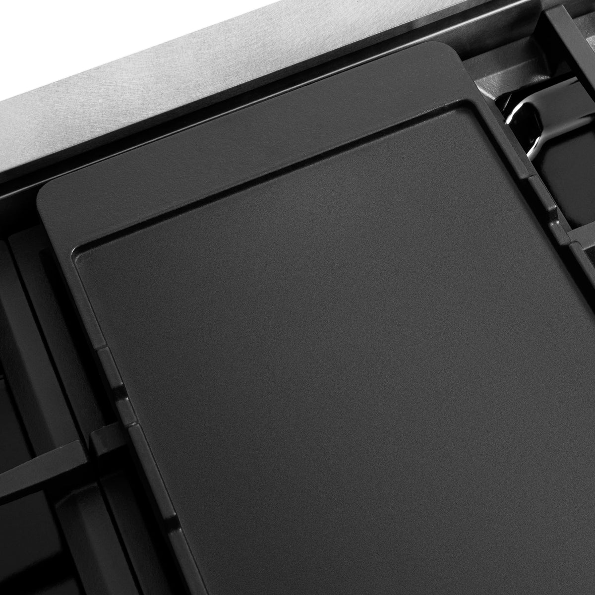 Flat black cooktop insert with matte surface and surrounding range grates