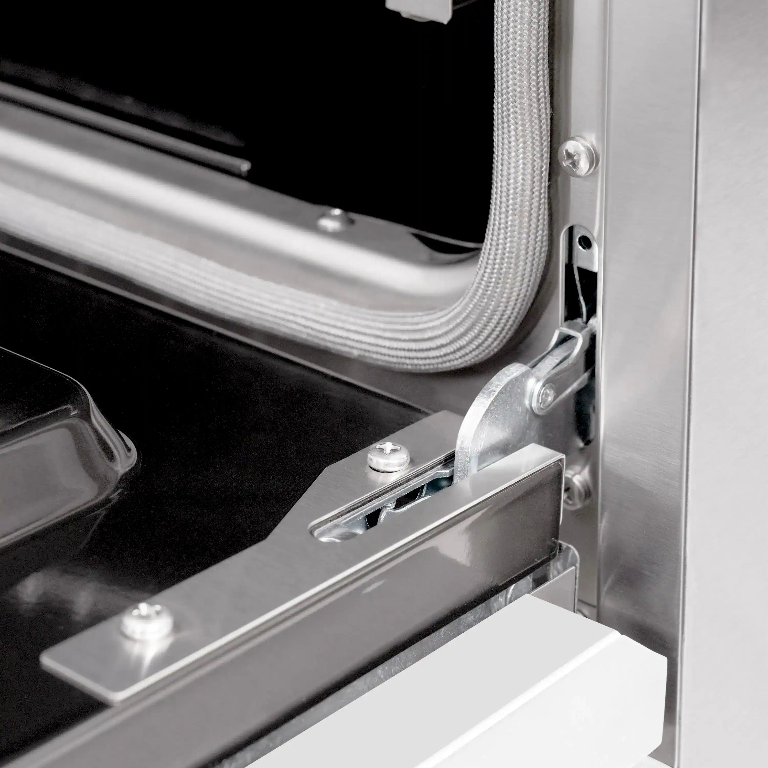 Stainless oven door latch and hinge hardware near the oven opening