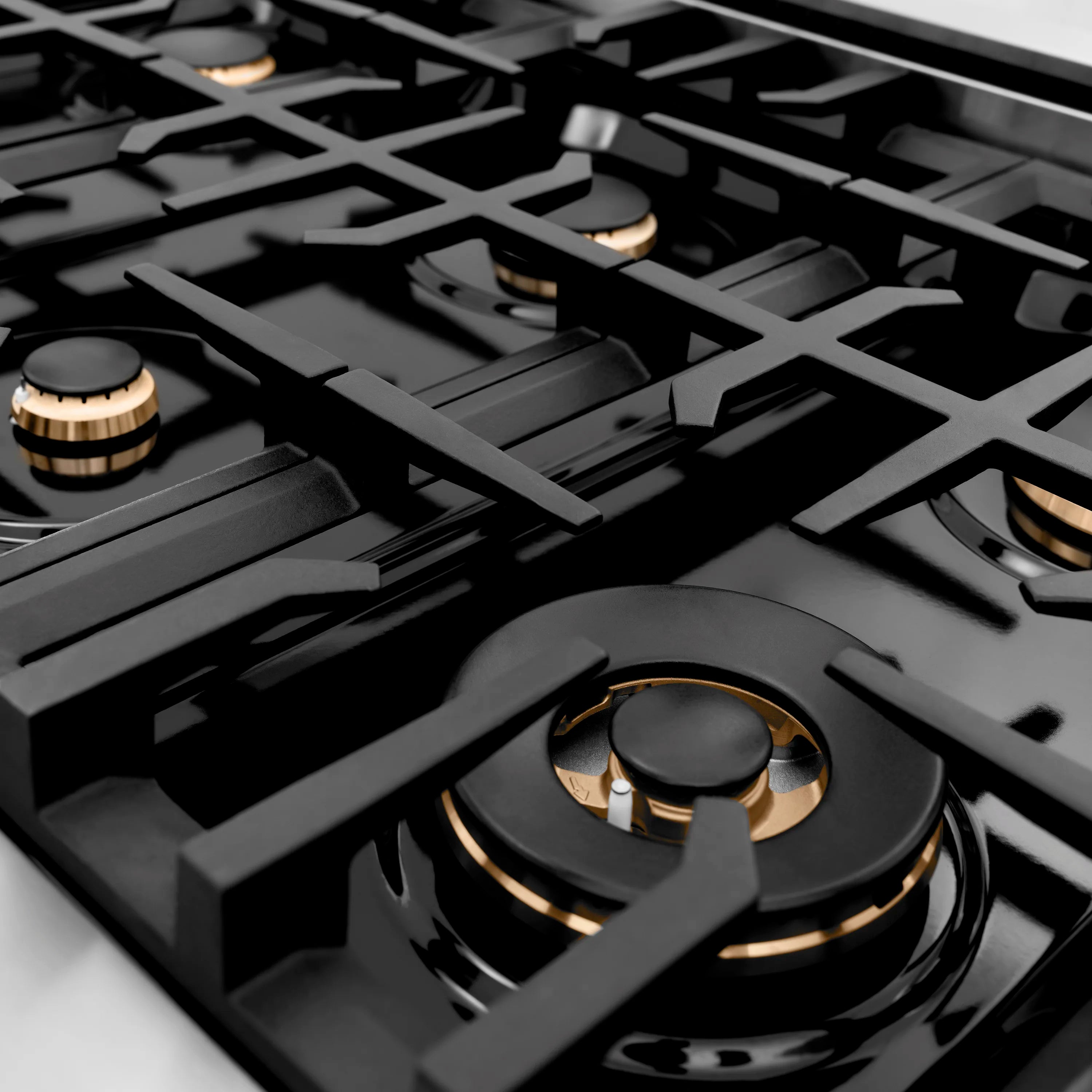 Black gas cooktop surface with grates and brass-accent burner caps