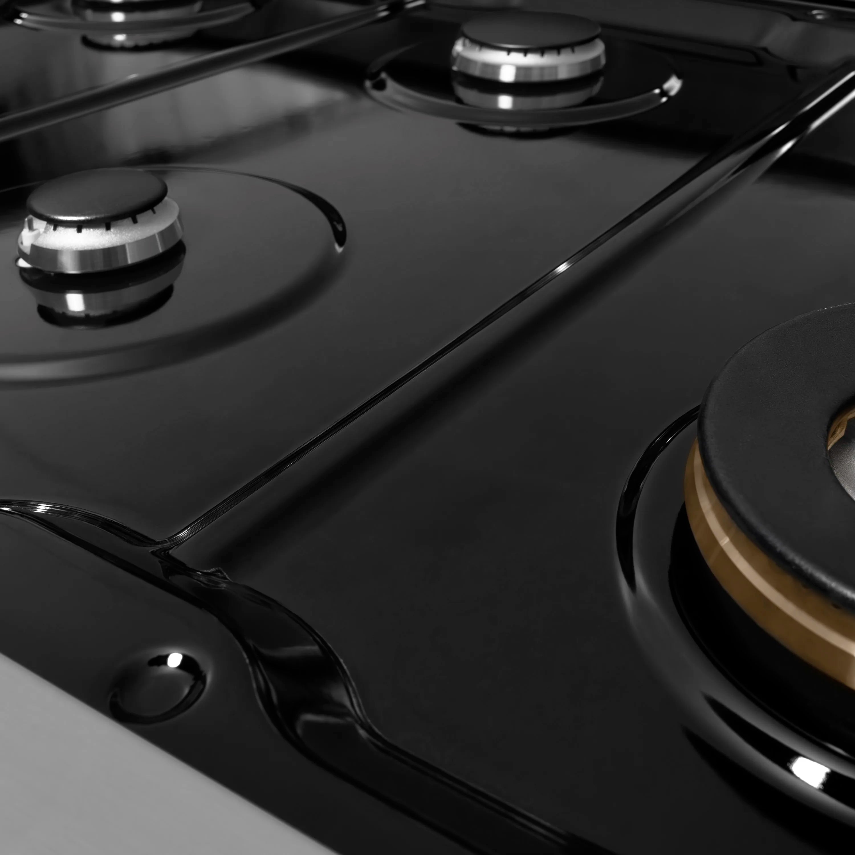 Black electric cooktop surface with round burner elements and brushed control panel edge