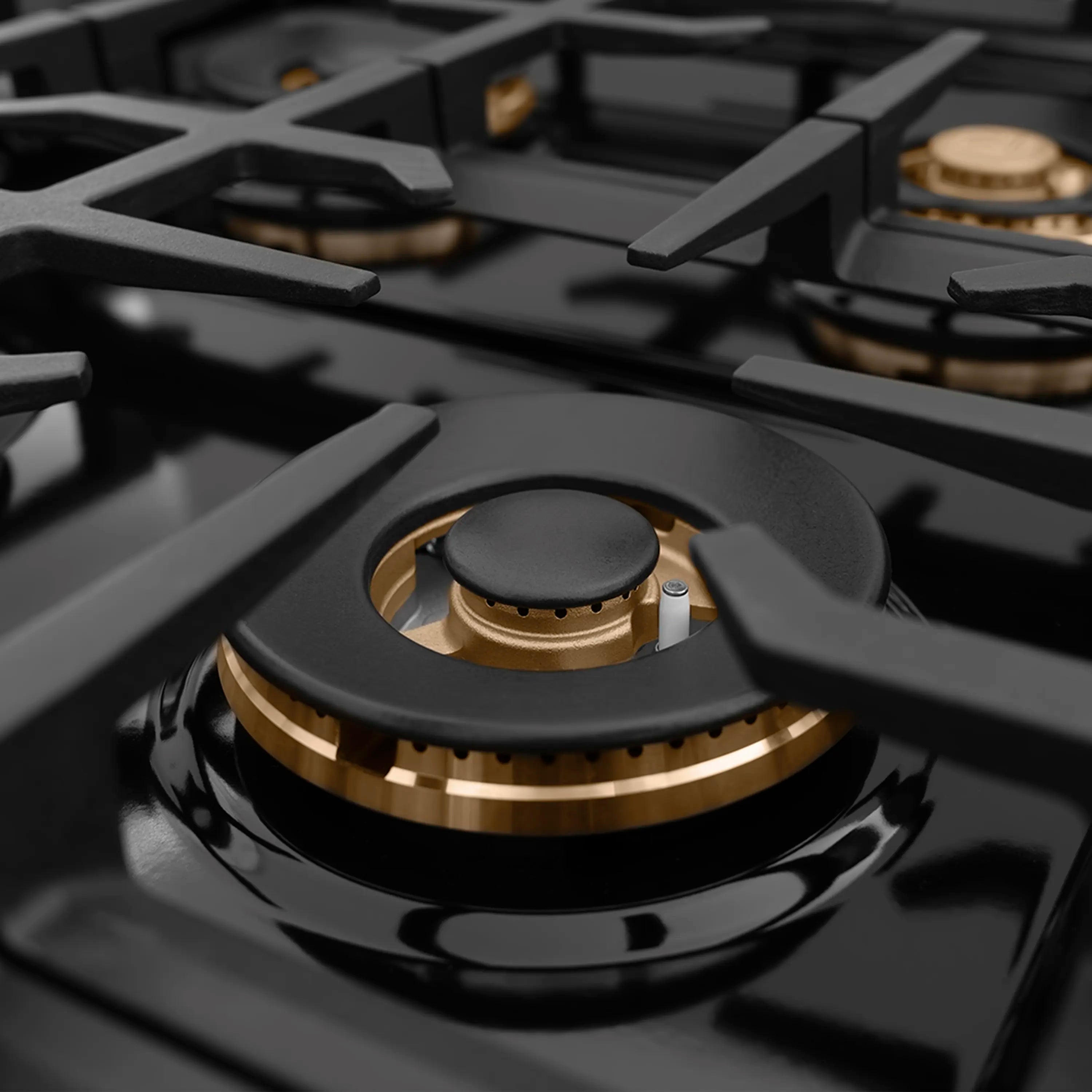 Brass gas burner with black cap on a glossy black cooktop grate