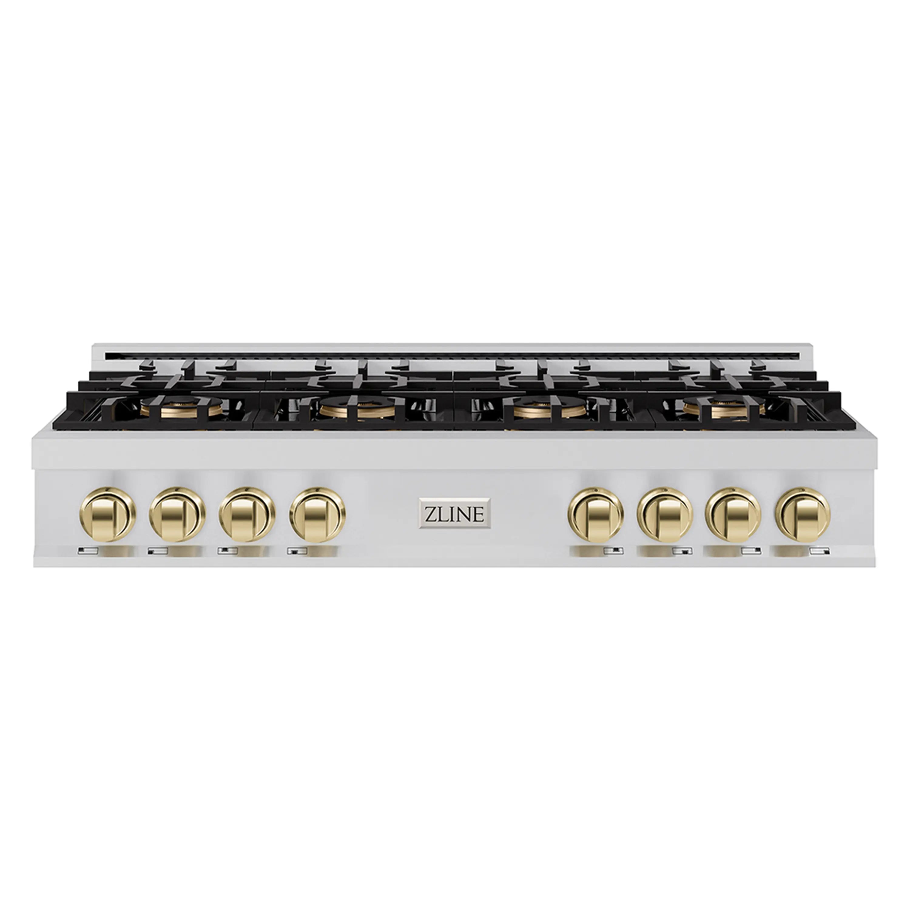 Stainless steel gas cooktop with black grates and polished gold control knobs