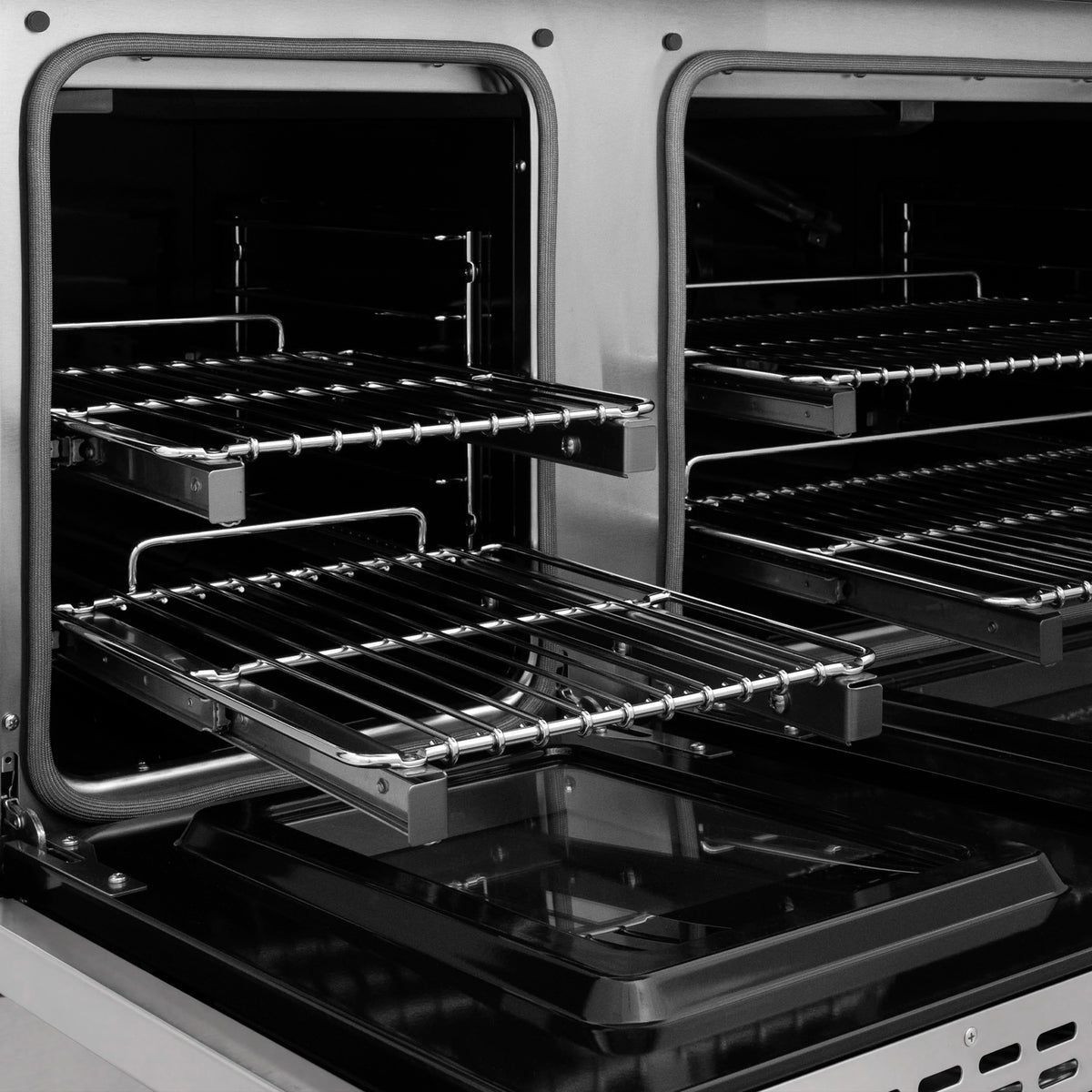 Open dual ovens with black racks and chrome rails inside stainless steel gas range
