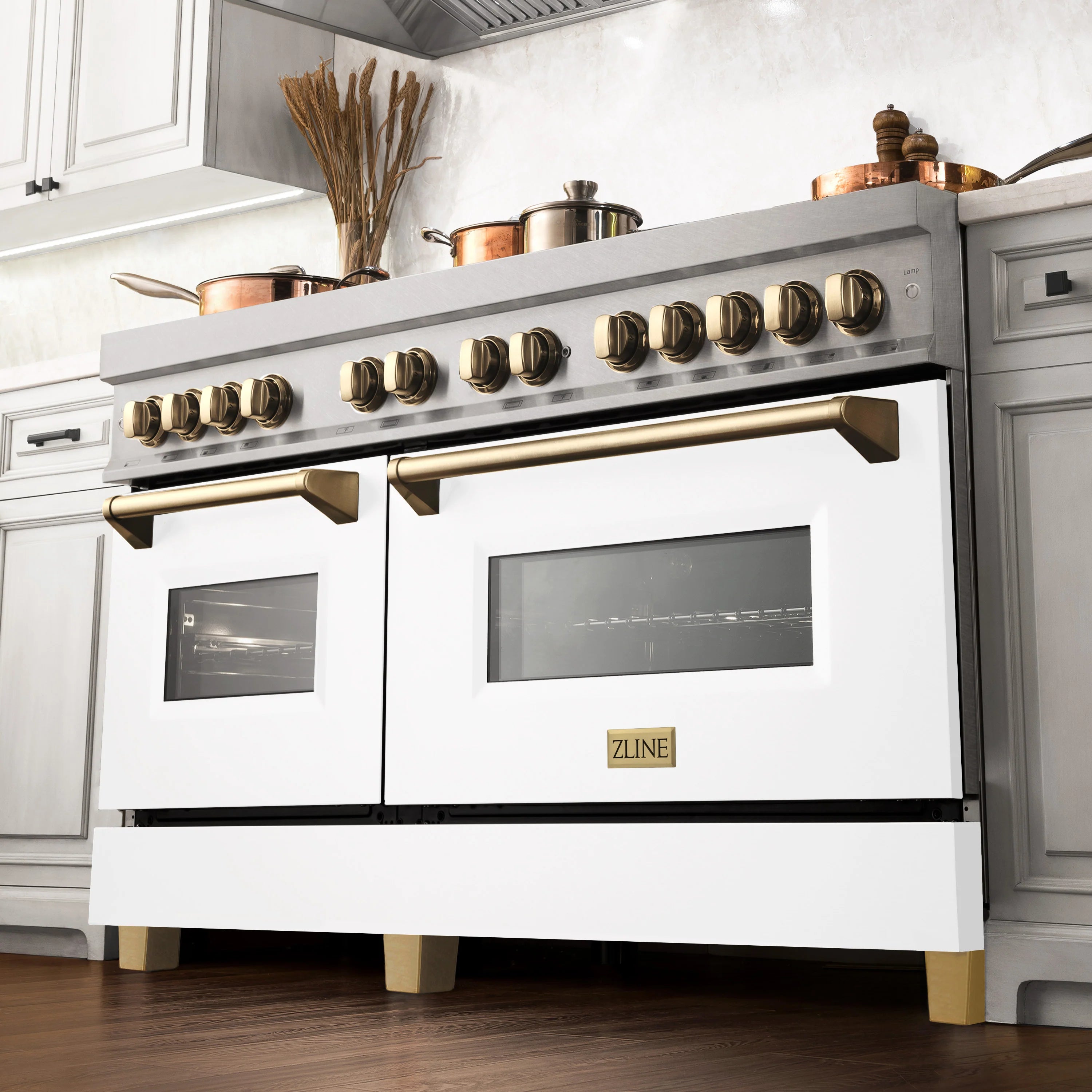 Dual fuel range with white oven doors, gold control knobs, and stainless trim above burners