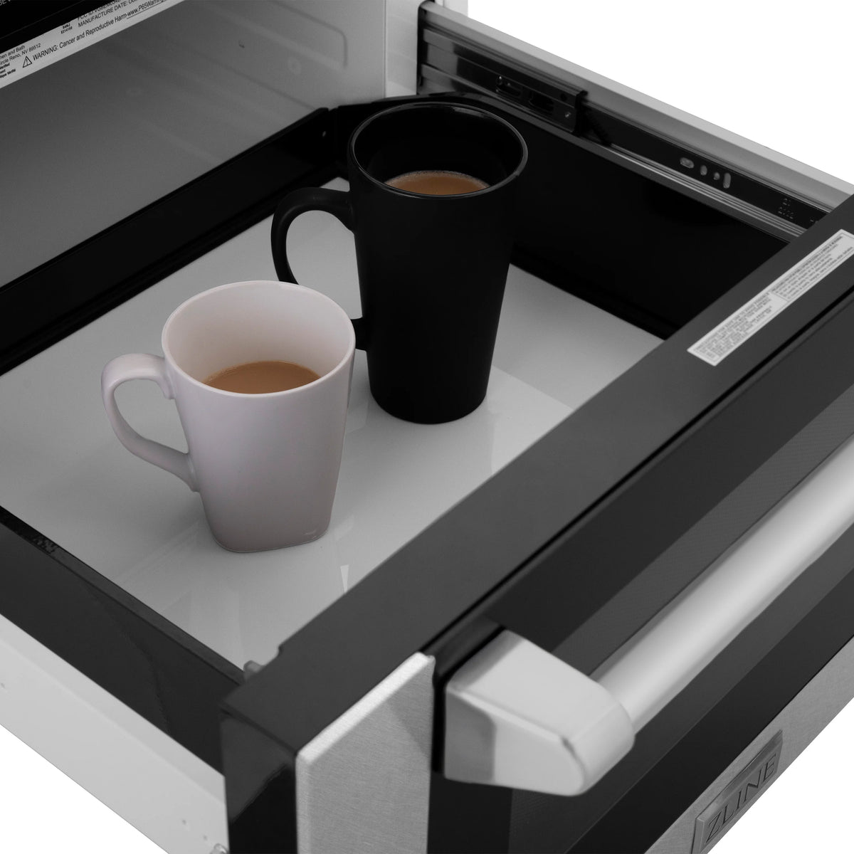 Microwave drawer open with cups inside the cooking chamber