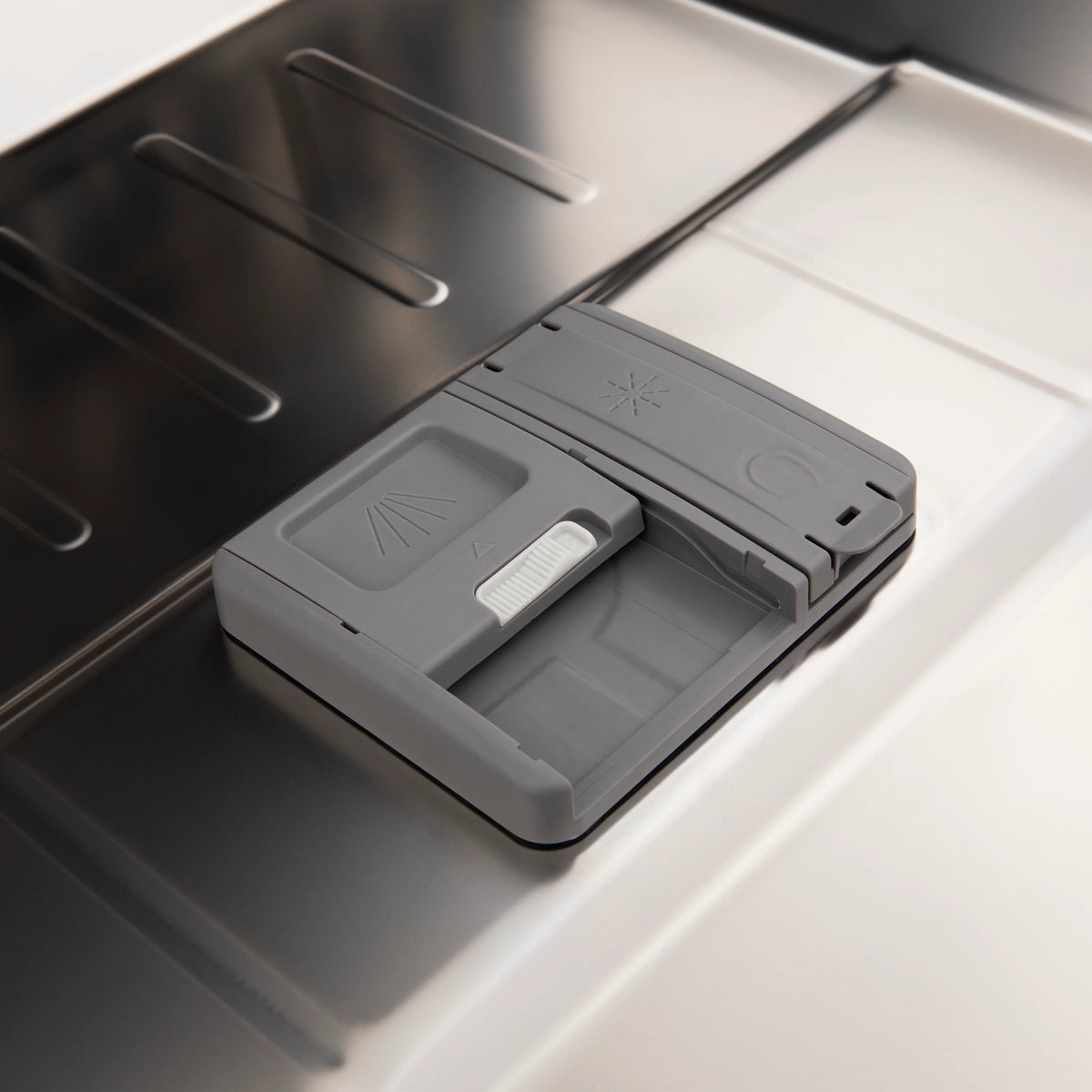 Dishwasher detergent dispenser on satin stainless tub interior.