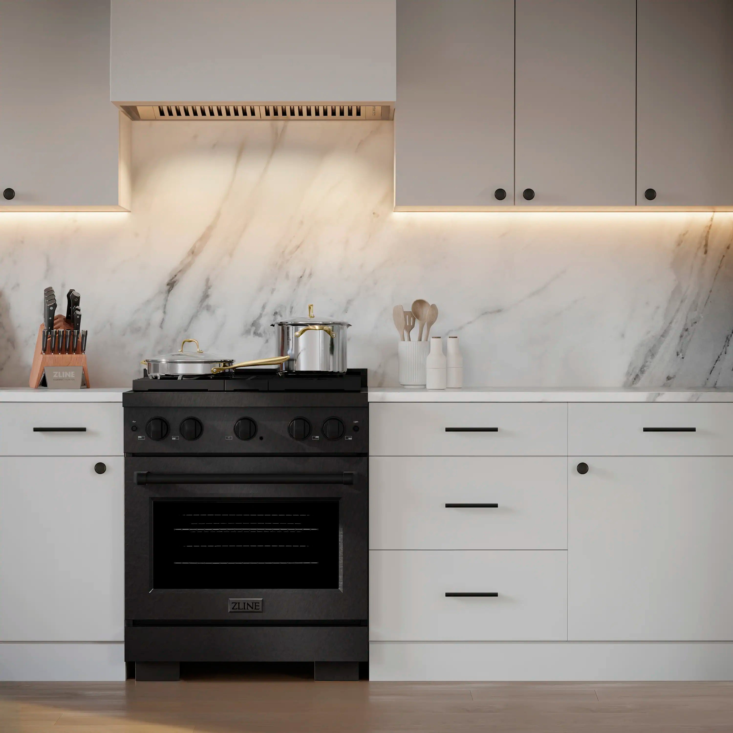 Black dual fuel range with gas cooktop and four brass-trim burners, stainless finish