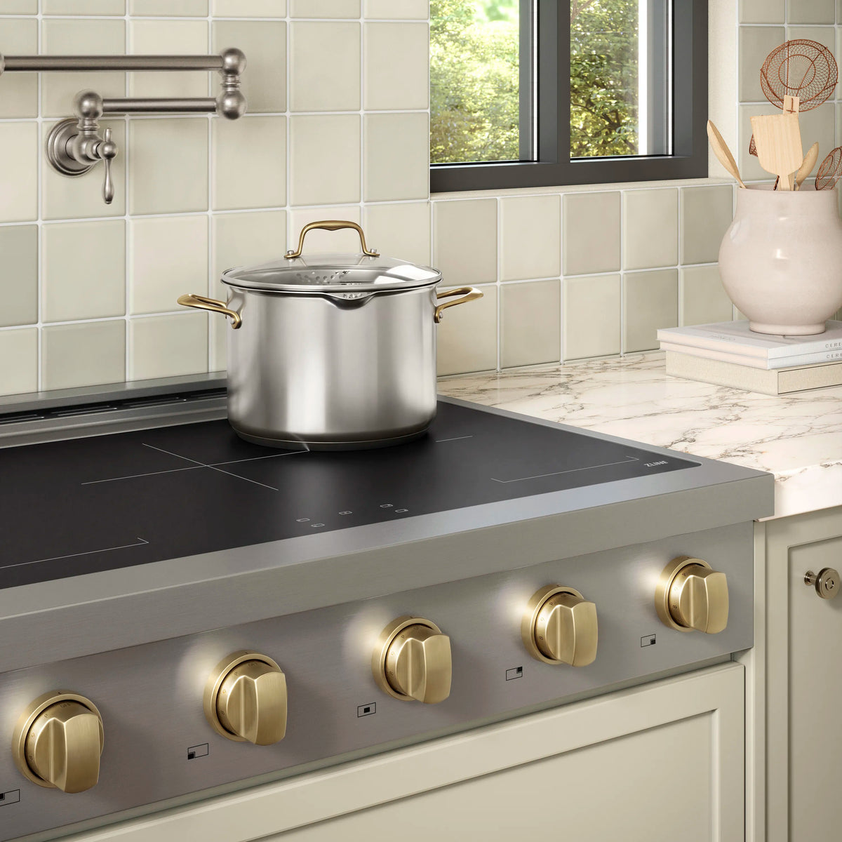 Stainless induction cooktop with bronze knobs and a covered pot on dark glass surface