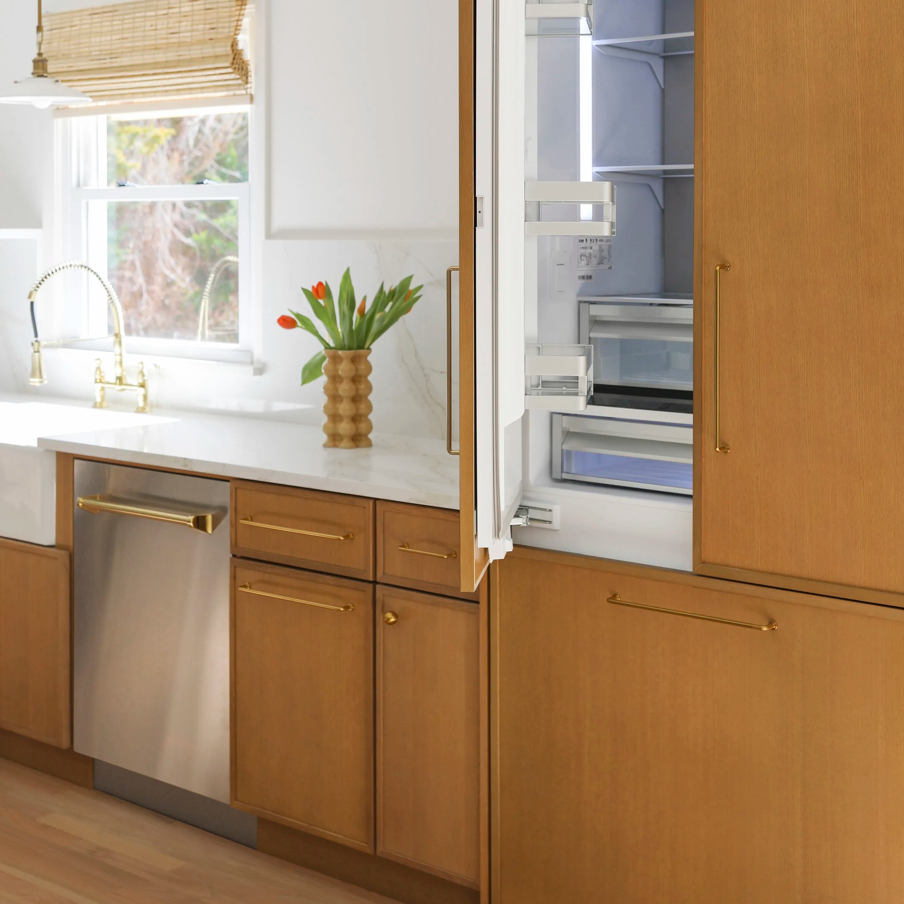 Open dishwasher door with gold handle and stainless inner cavity, built-in fit