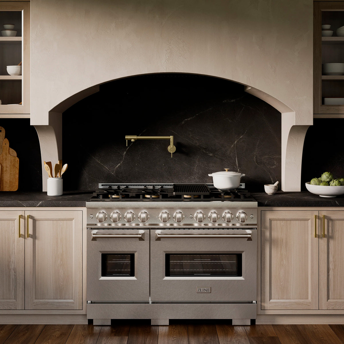 Stainless steel freestanding gas range with twin ovens and lit burners on cooktop