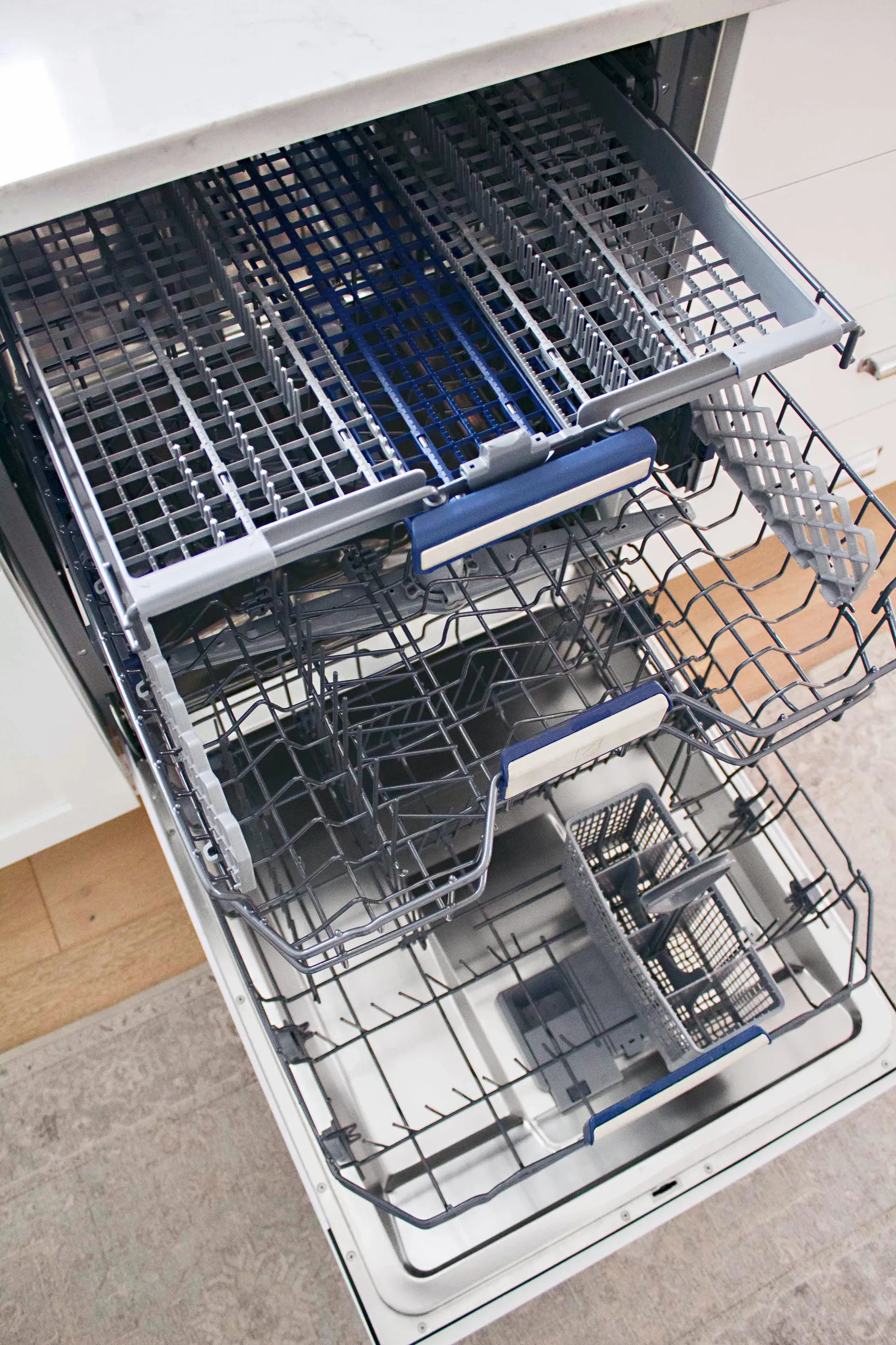 Dishwasher open with top rack and silver wash arms visible