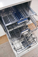 Dishwasher interior with upper rack and loading tines, open-door view