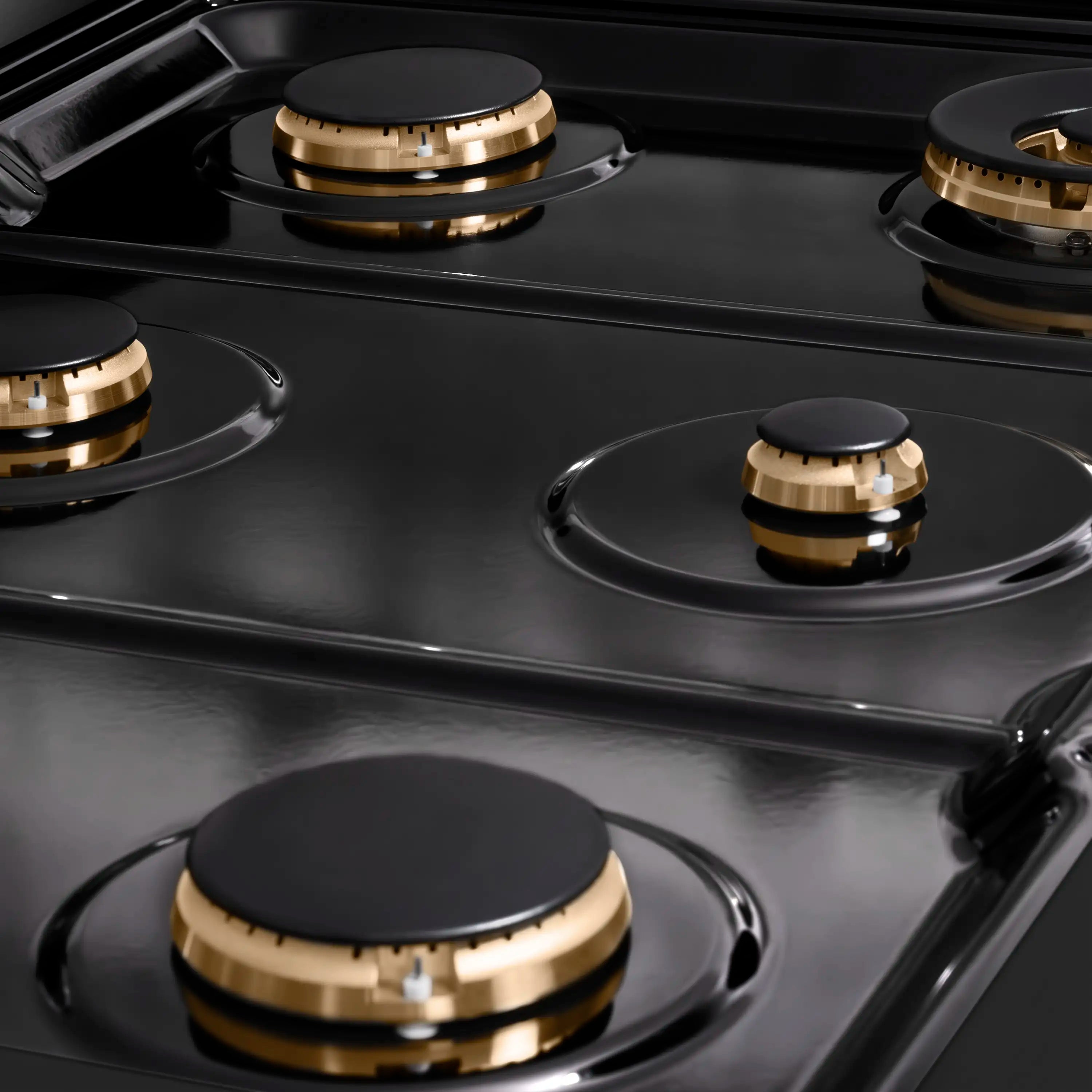 Black gas cooktop with circular burners and gold-accent burner rings