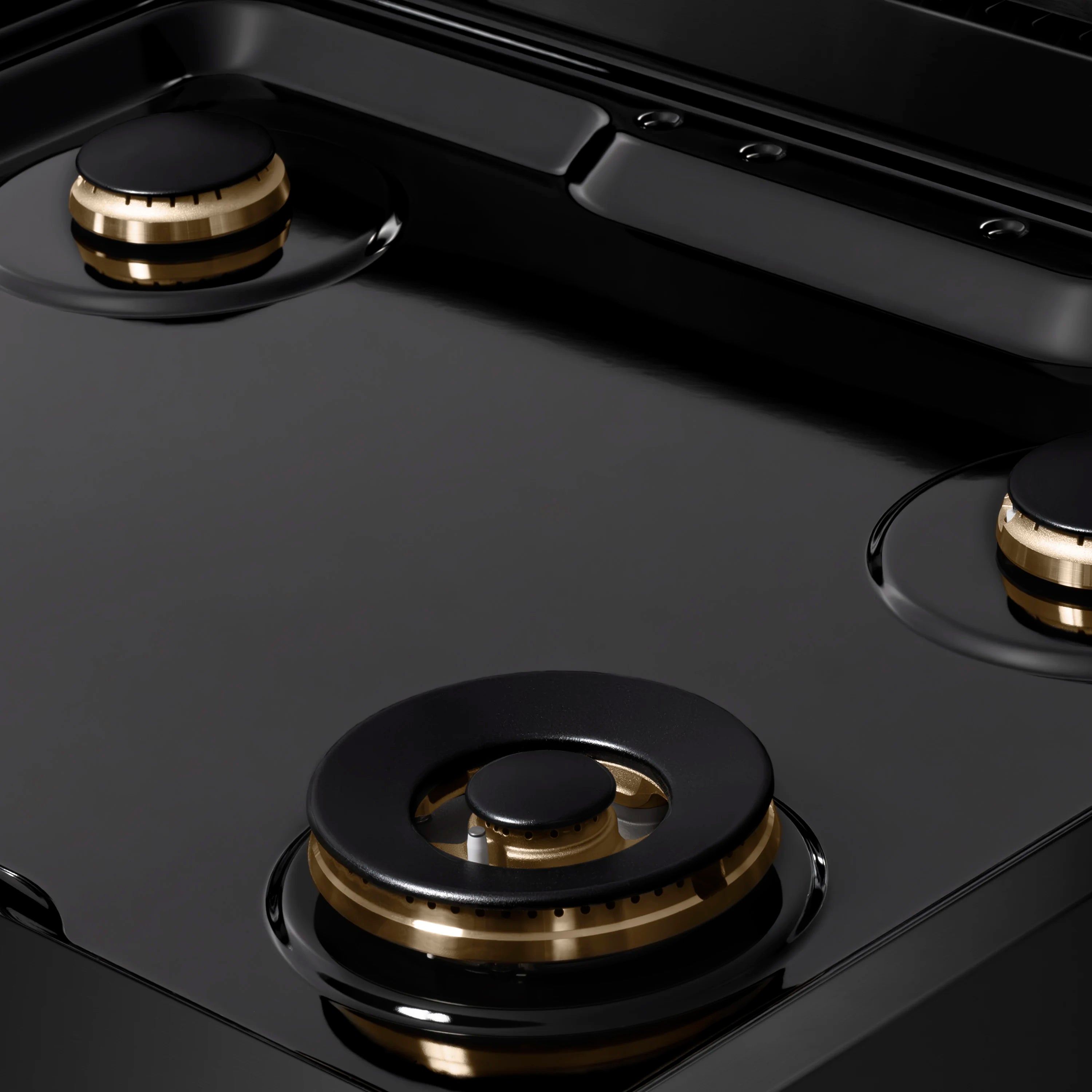 Black gas rangetop with dual burners, black grates, and polished gold burner rings