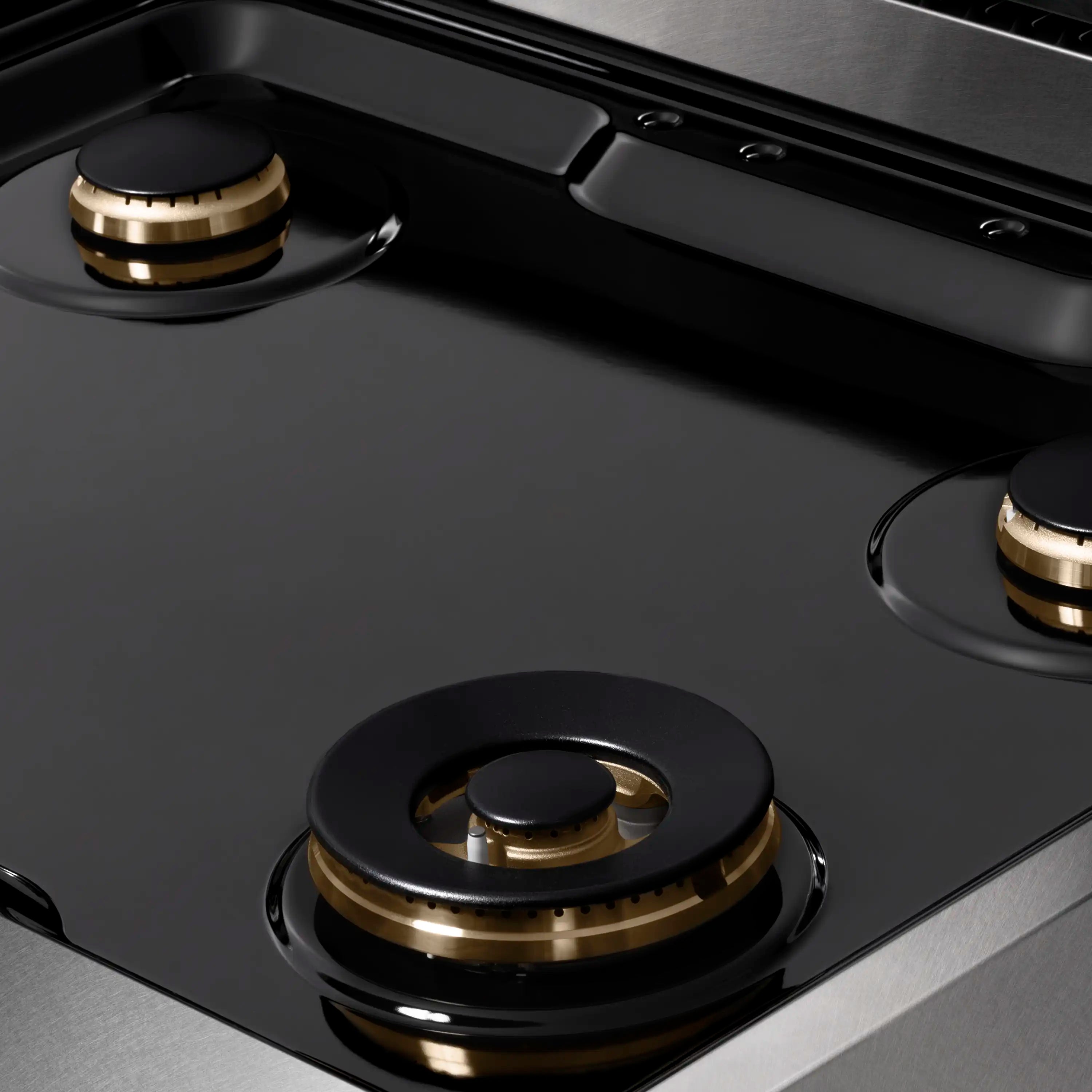 Black burner caps with gold-trimmed burner heads on dark cooktop surface