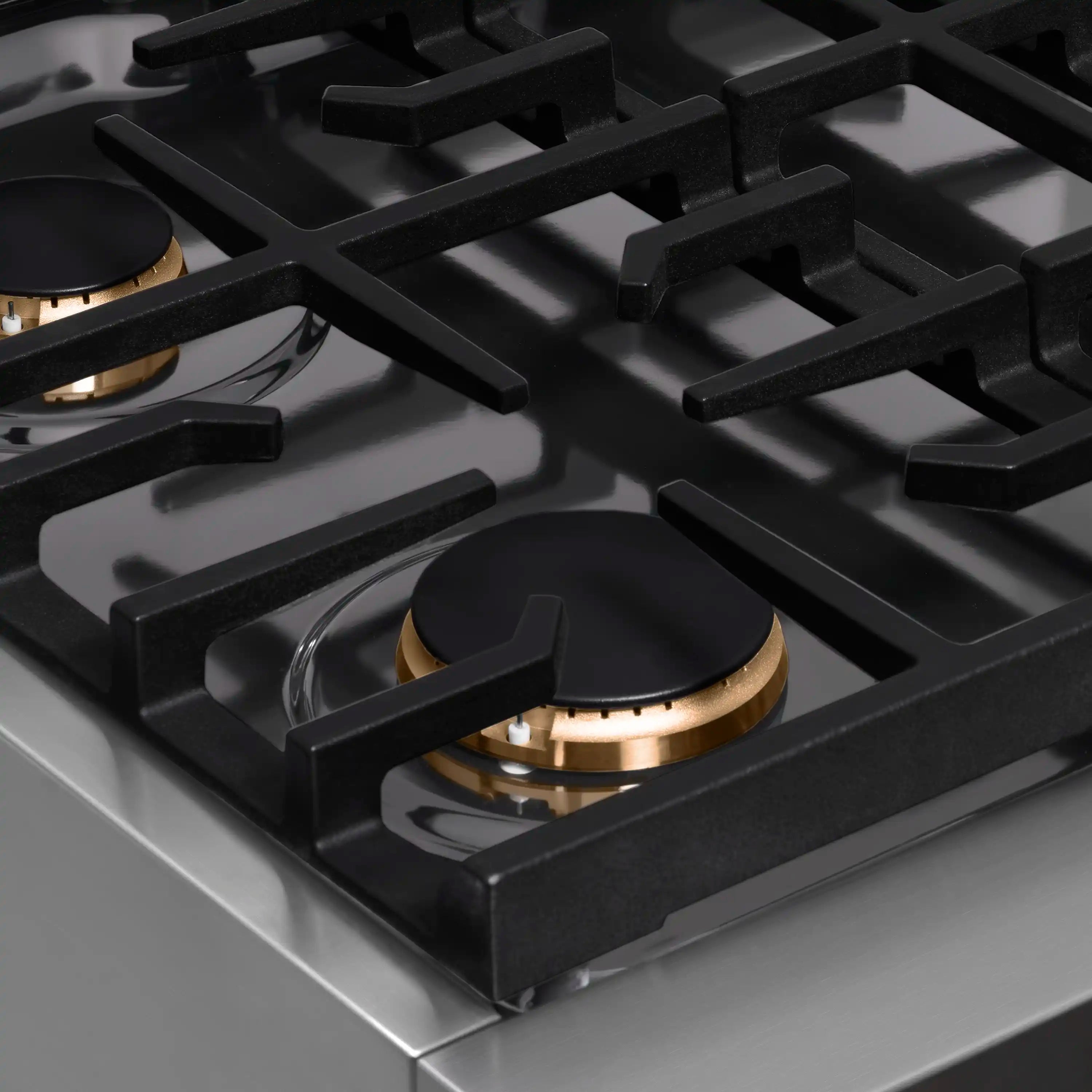 Close-up of black grates and a black burner cap with champagne bronze ring on a 4-burner gas top