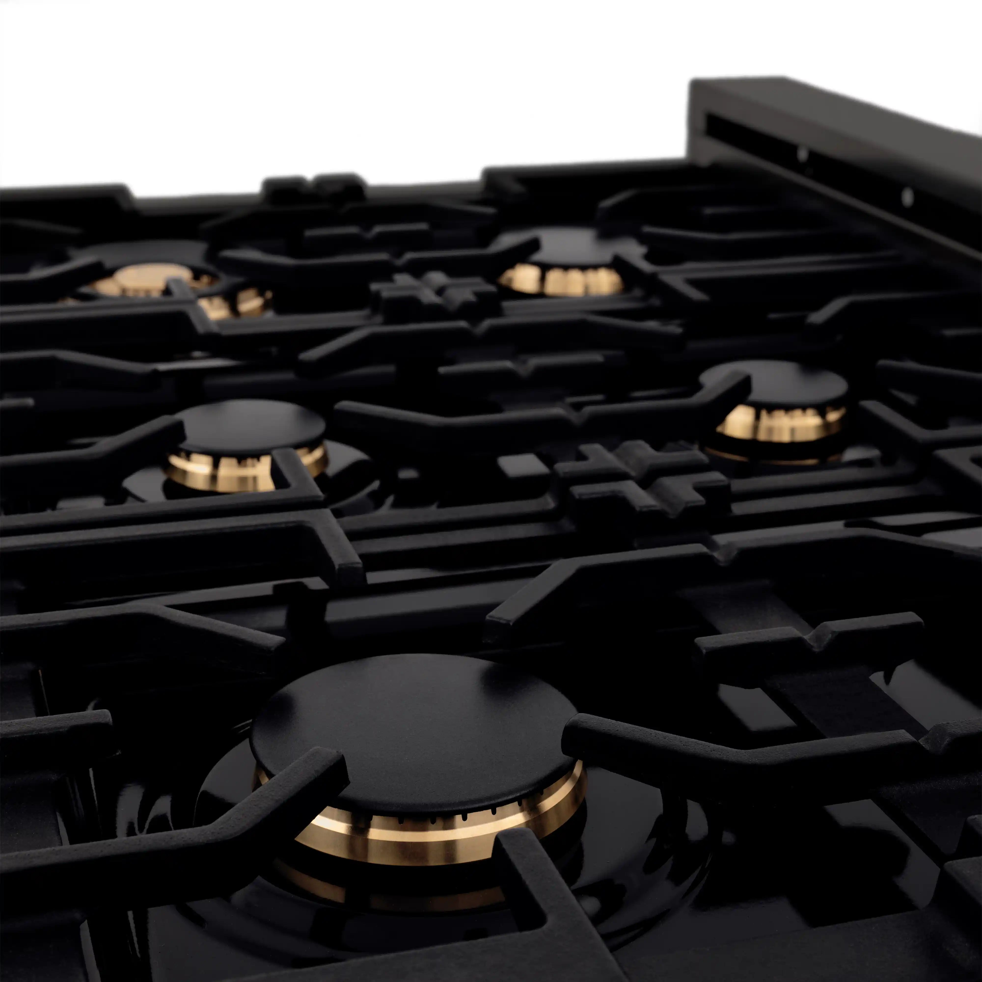Close-up of black gas rangetop grates and burner heads with brass-tone details