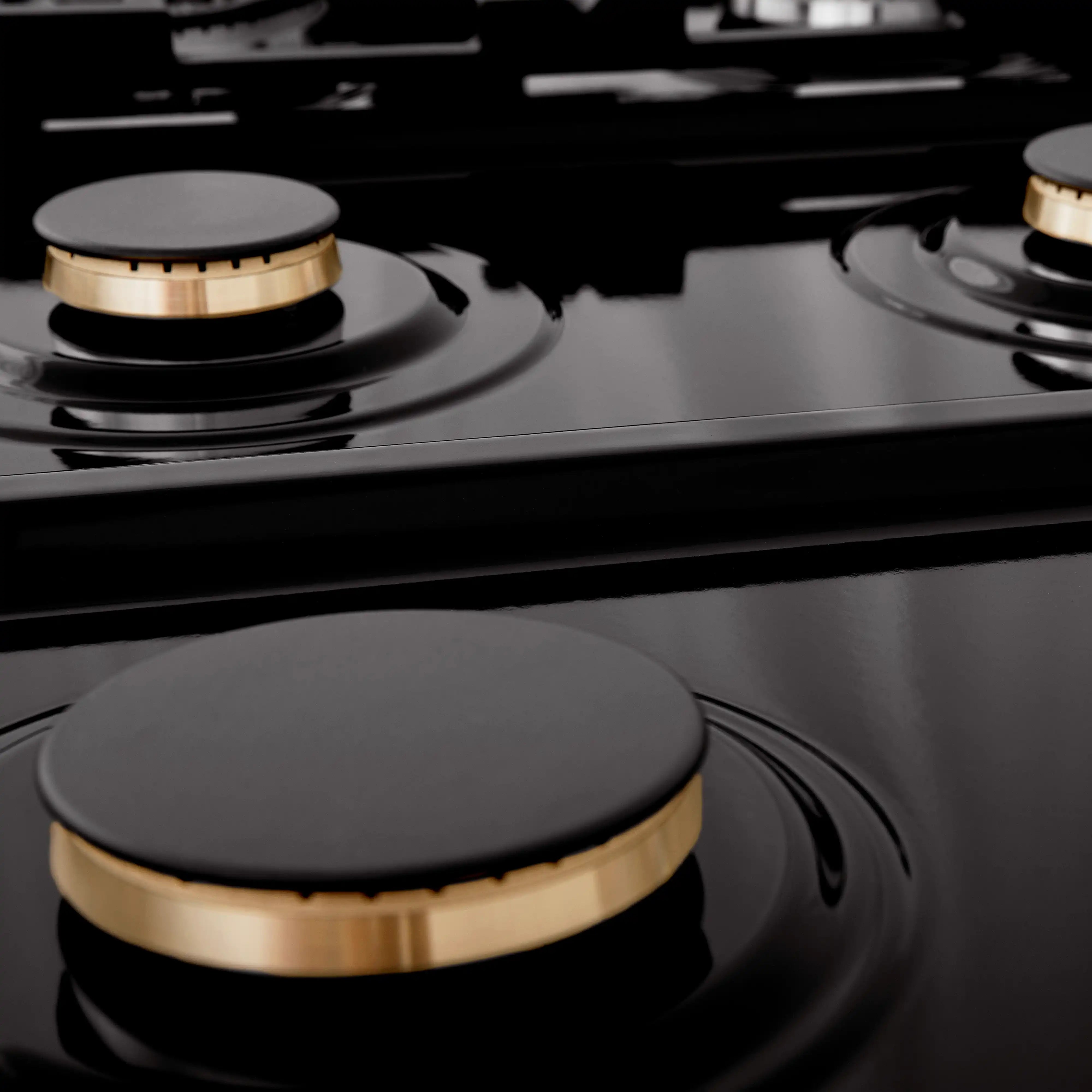 Close-up of black gas rangetop burner cap and front control knob with brass-tone trim
